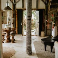 Cozy living room with wooden furniture, a piano, and large glass doors opening to a garden.