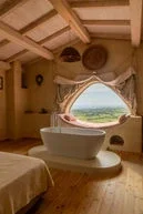 A cozy bedroom with a clawfoot bathtub next to a large window with a scenic view.