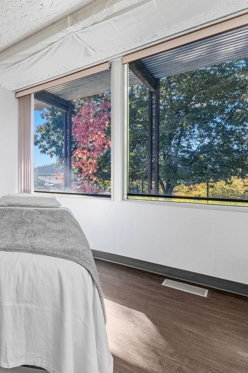 A treatment table facing wide windows with autumn tree.