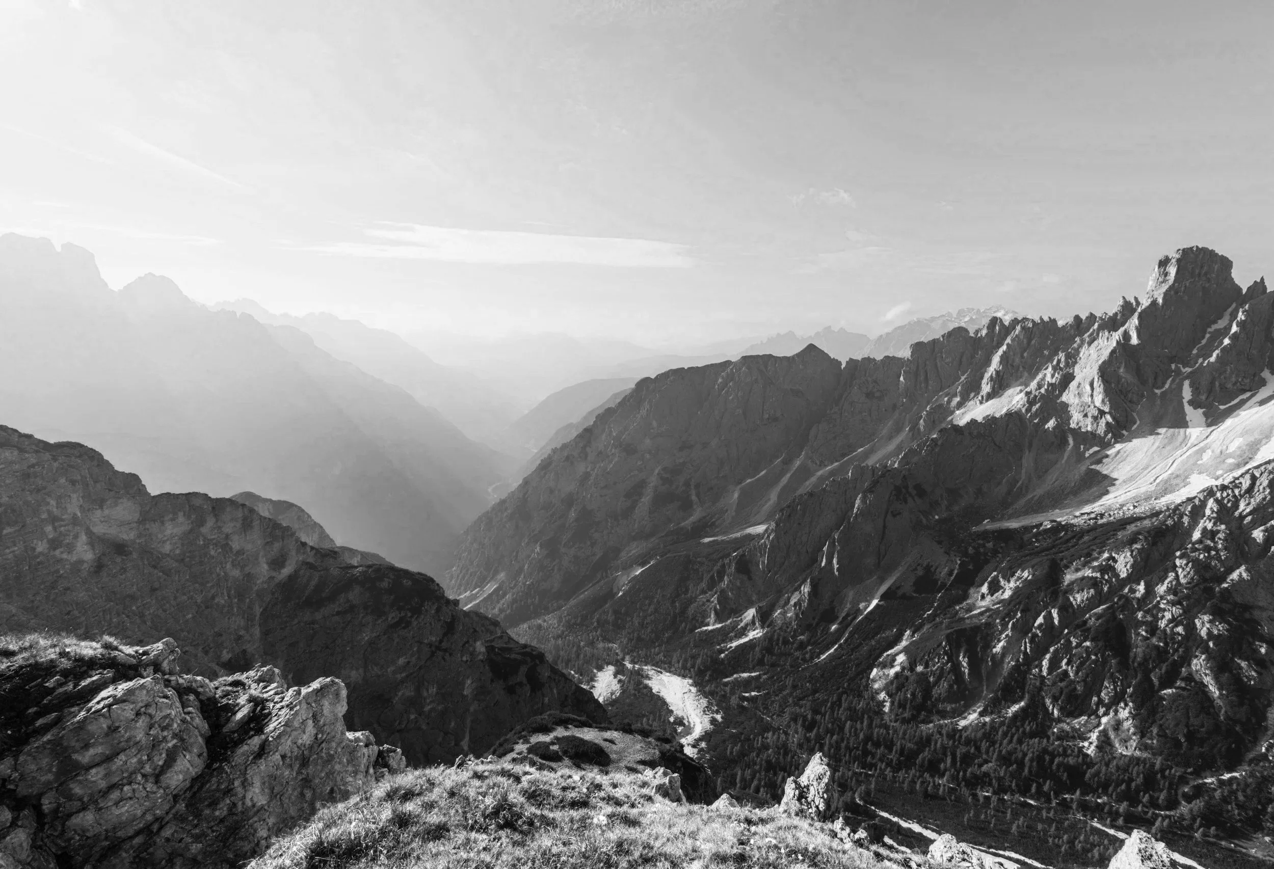 Black and white photo of a mountain range with rugged peaks and a valley below.