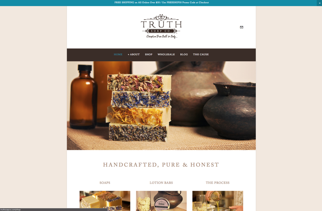 Stacks of soap bars with dried flowers, bottles, and rustic pots on a table, representing a handcrafted soap company.