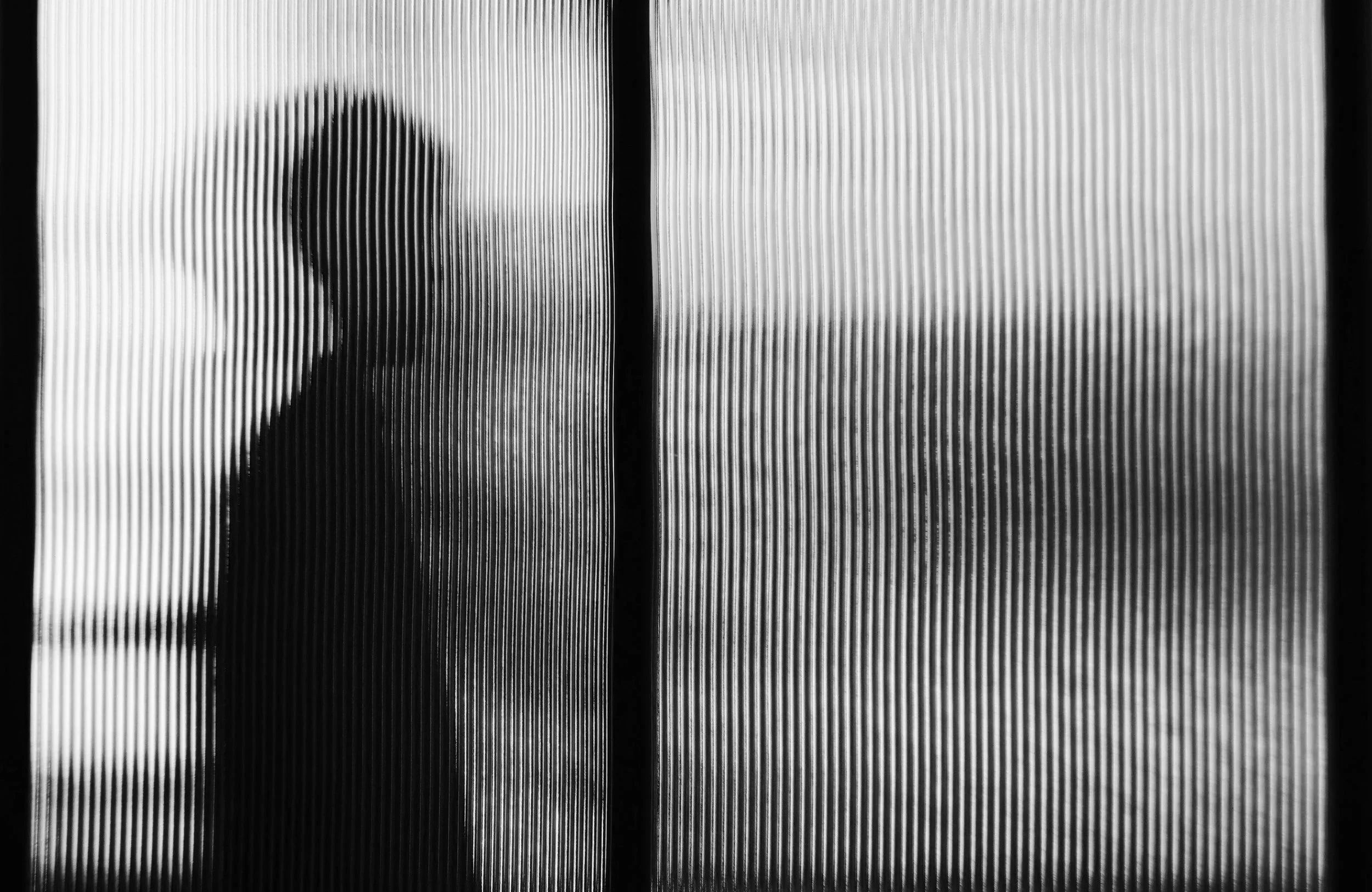 Silhouette of a person behind a textured glass door or window.