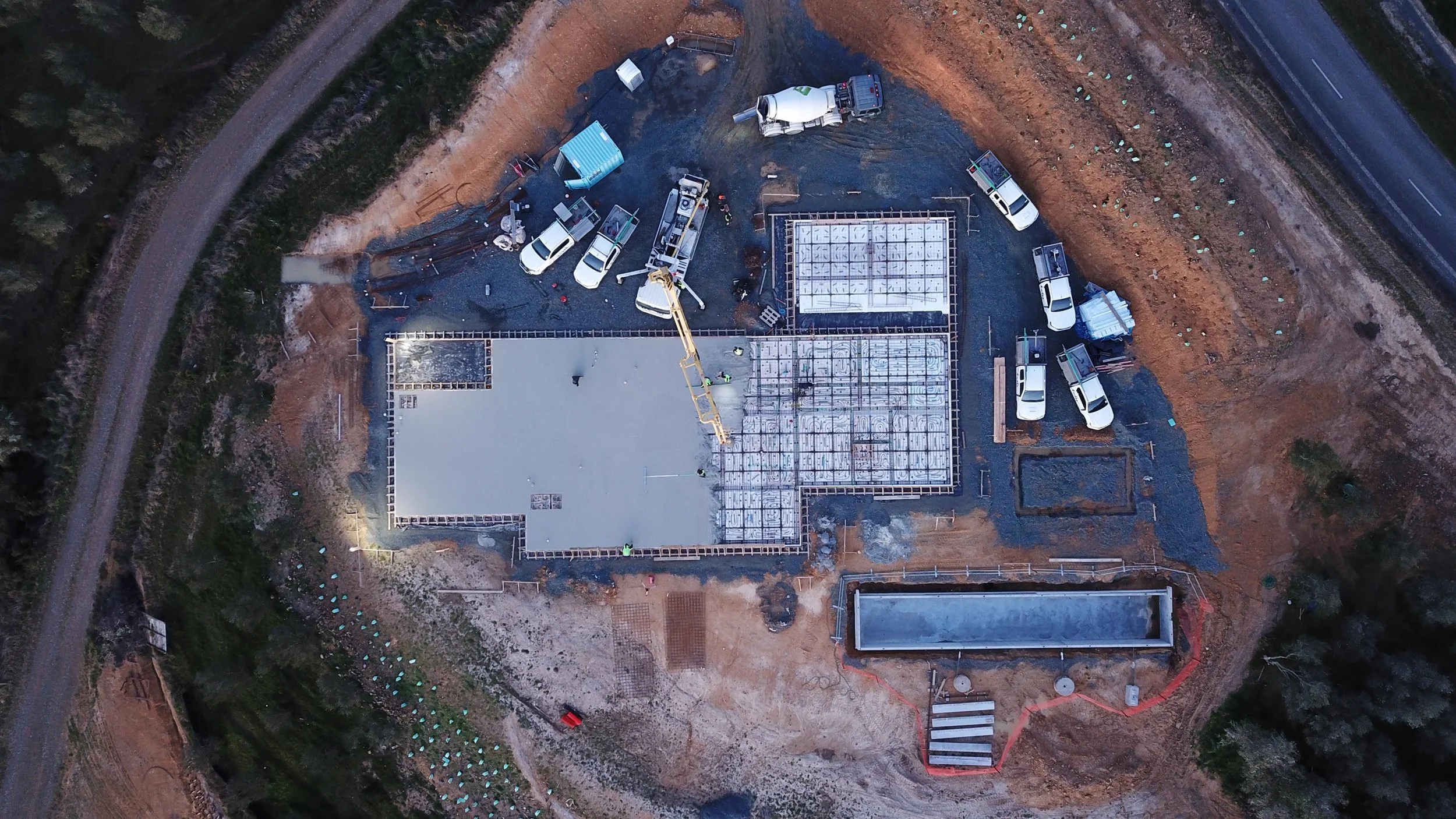 An aerial view of a construction site showing foundation work, construction vehicles, and workers building a structure