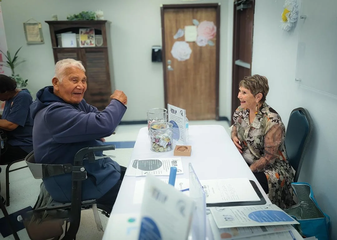 Two people sitting across the table from one another talk.