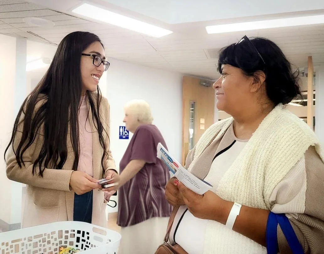 Two women holding brochures talk