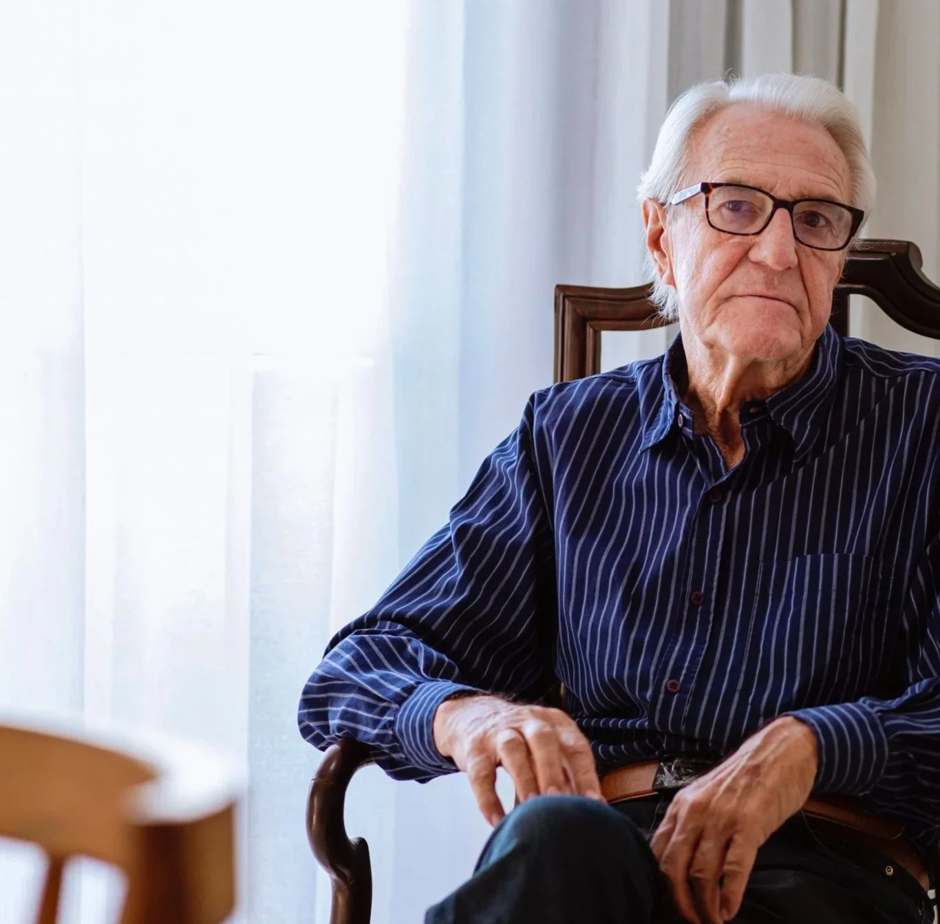 Man sitting in chair wearing glasses