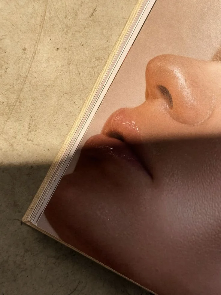 Close-up of a face, focusing on the nose and lips, reflected on a shiny surface, with a textured background.