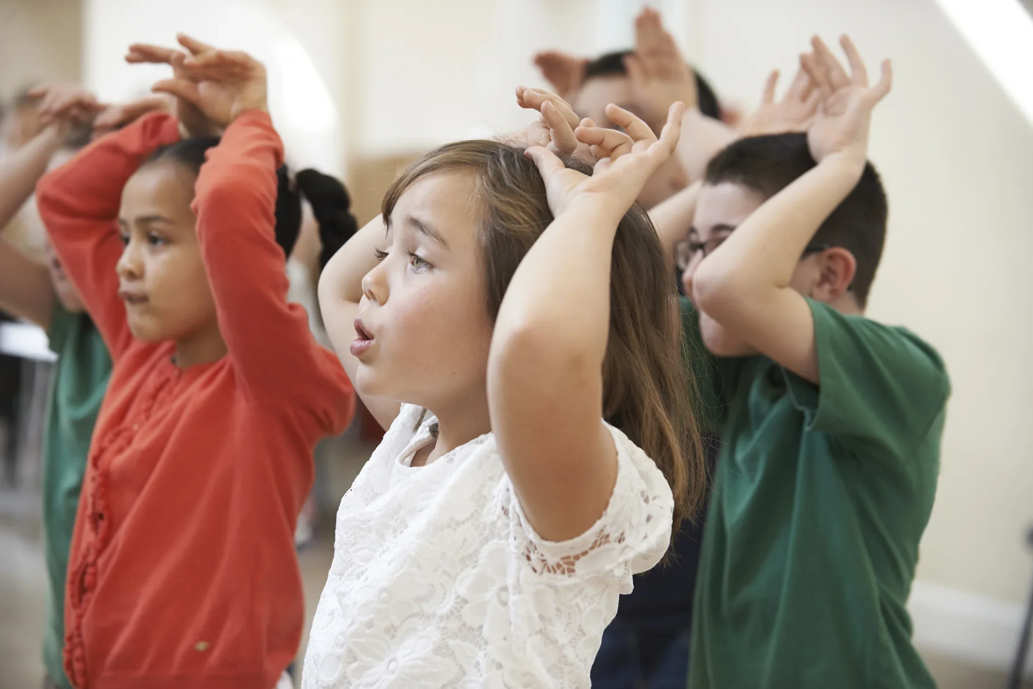 Children participating in a classroom activity, raising their hands and engaging in the lesson.