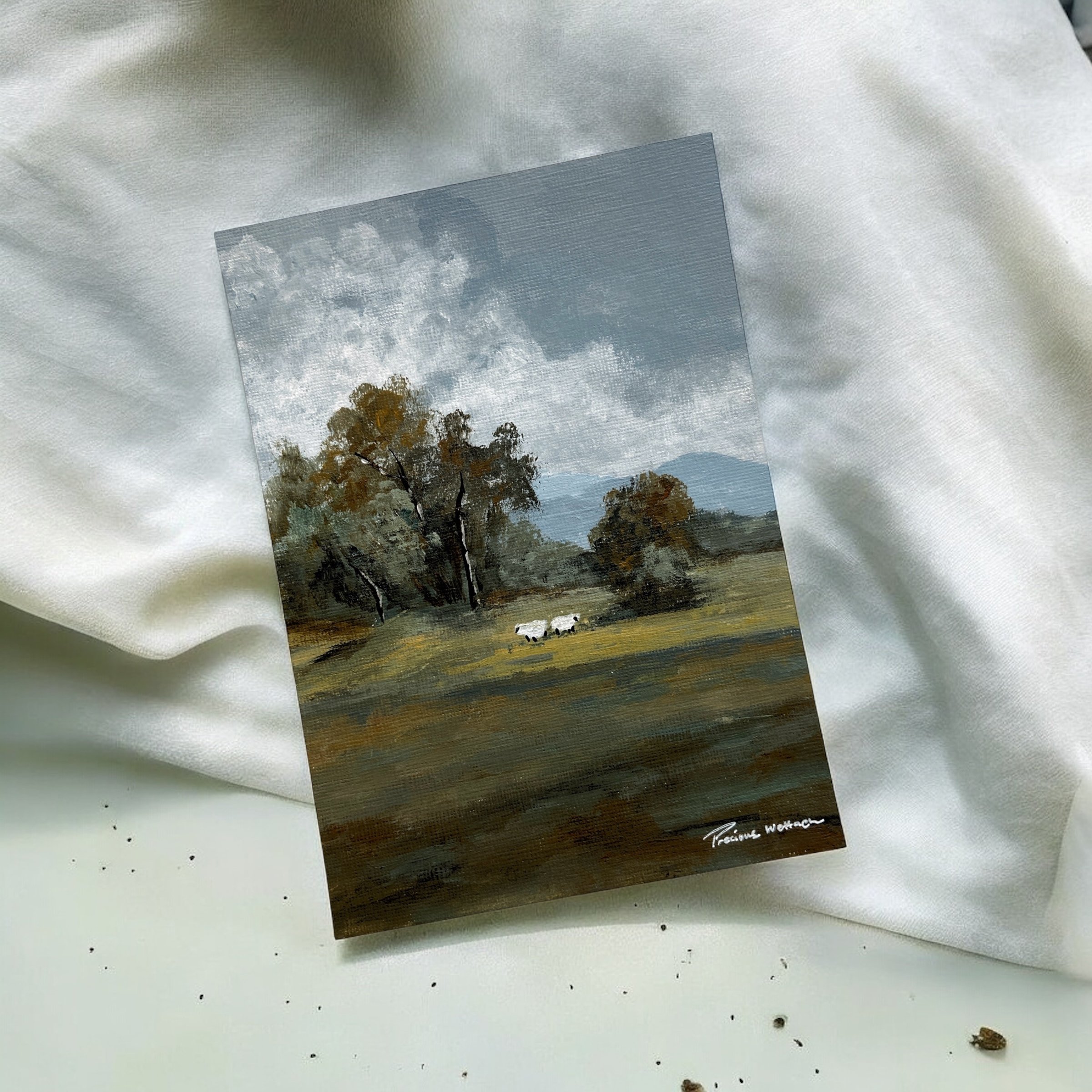 A landscape painting of trees, mountains, and a cloudy sky, with two cows grazing on a field.