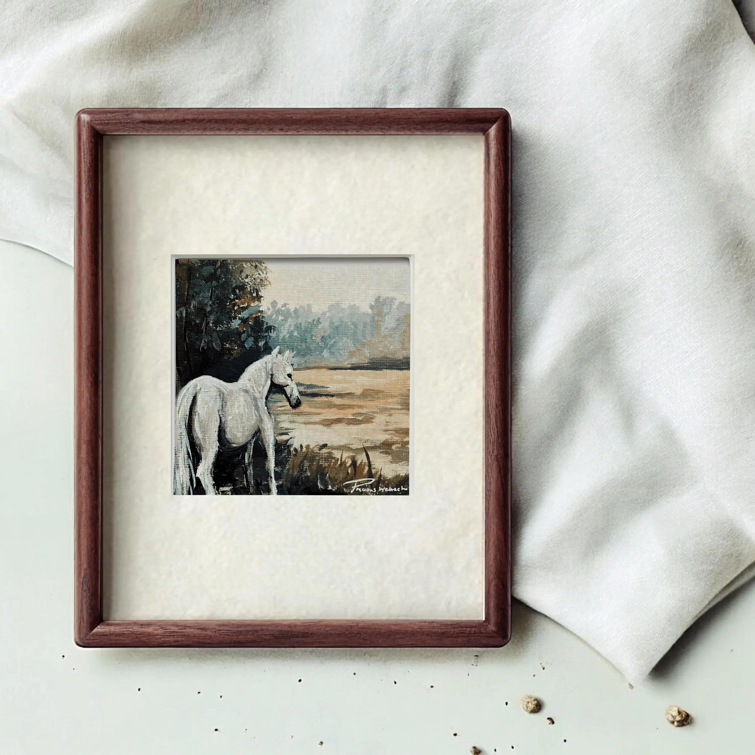 Framed miniature painting of a white horse standing by a lake with trees and sky in background, signature in lower corner.