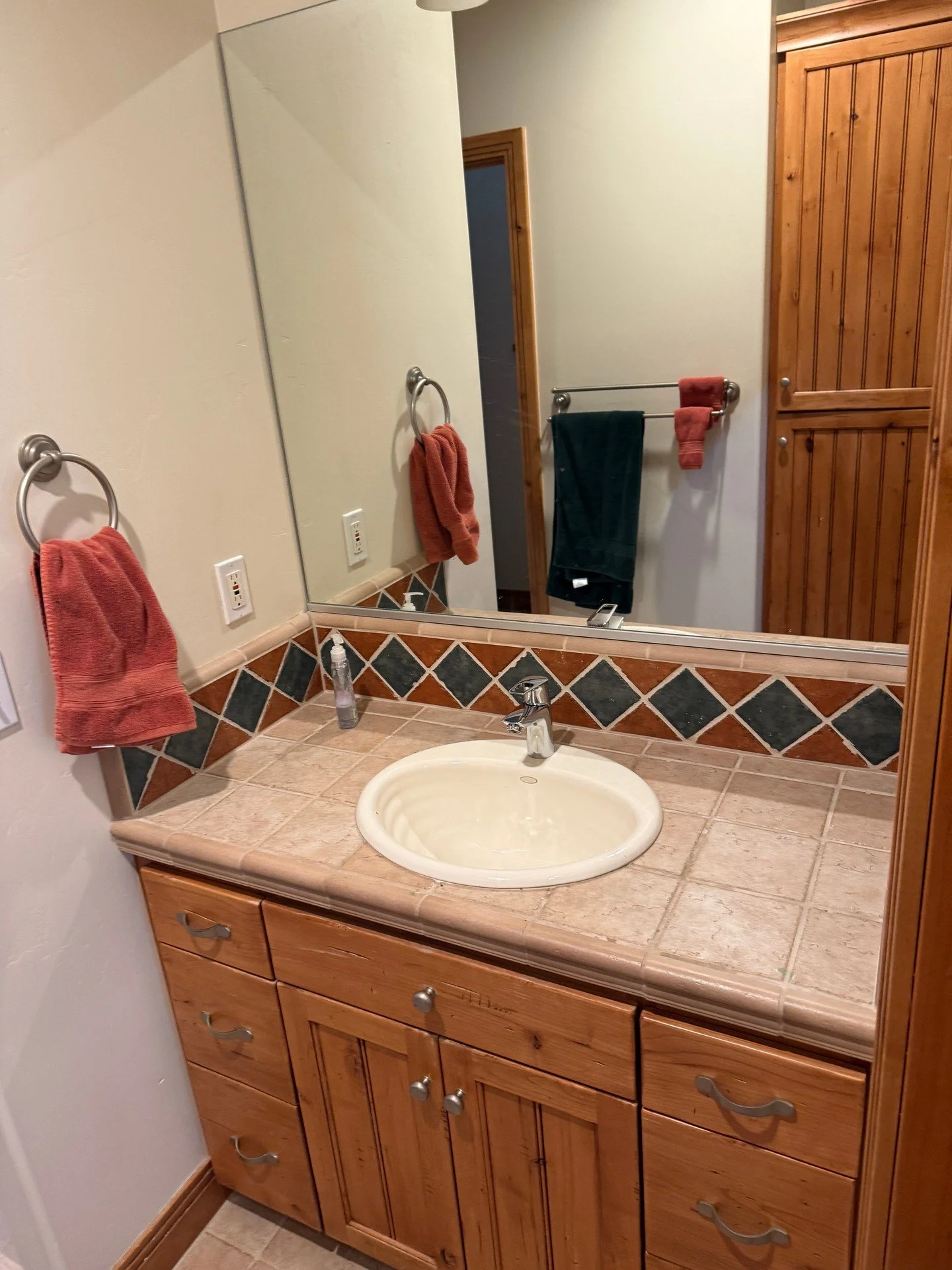 Clean, straightforward vanity job today. Drop-in sink with a single-handle faucet set square and centered, with supply and drain tucked out of sight. No leaks or water damage around the fixture, and the tiled countertop and backsplash are sealed to h