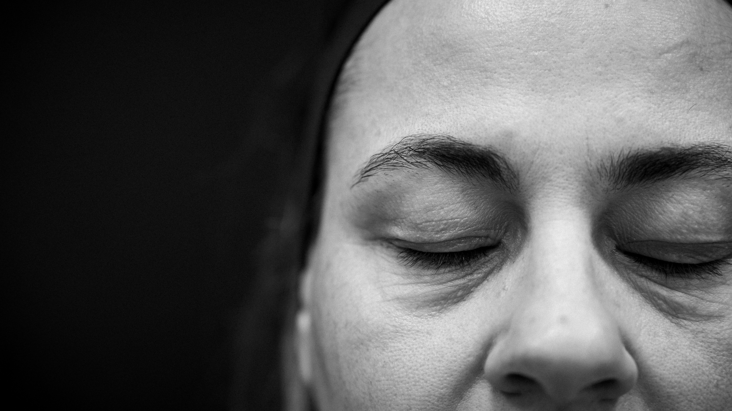 Primo piano di un volto di una persona con gli occhi chiusi, in bianco e nero.