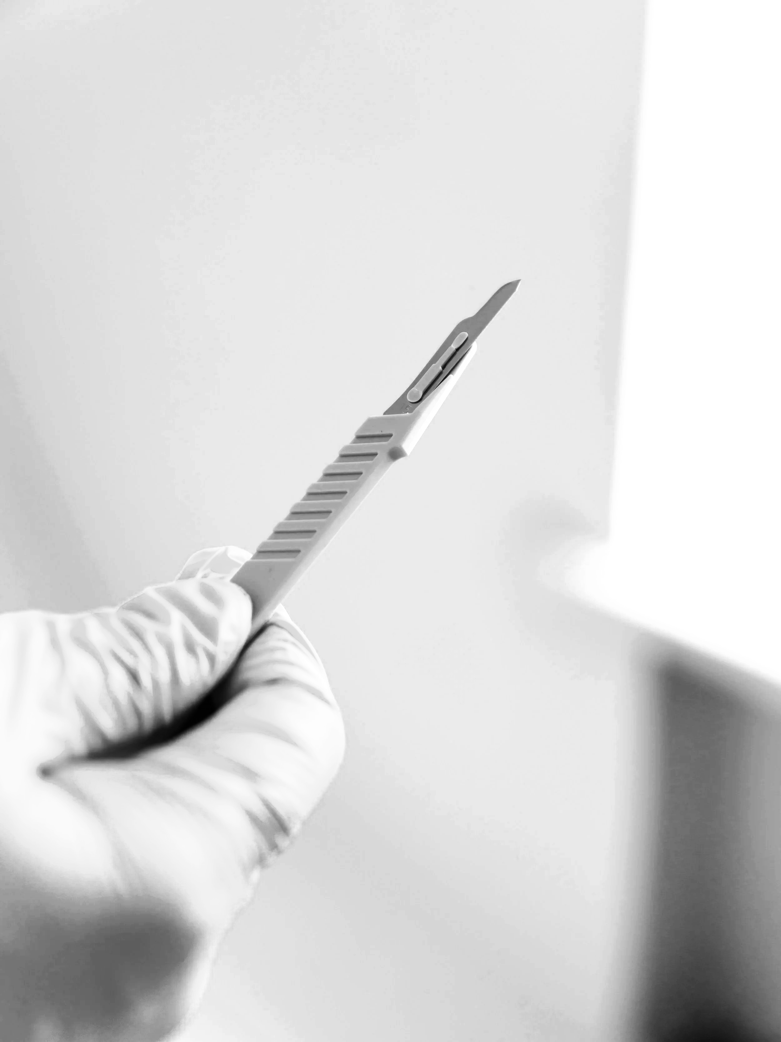 Mano con guanto usa un raspatutto in una stanza bianca.