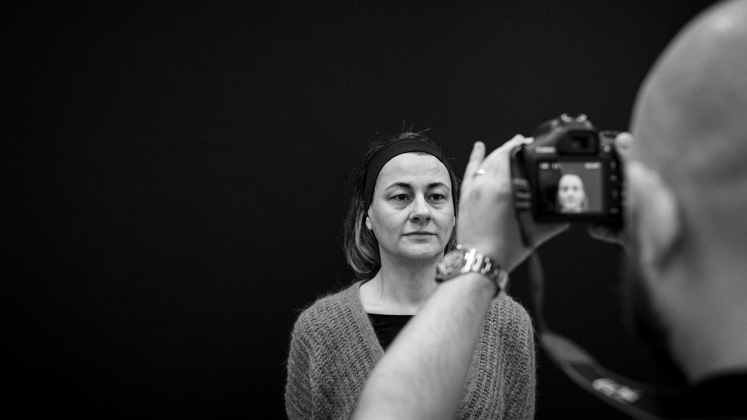 Donna che si fa ritrarre durante una sessione fotografica, con un fotografo che scatta una foto a sua volta, in bianco e nero.