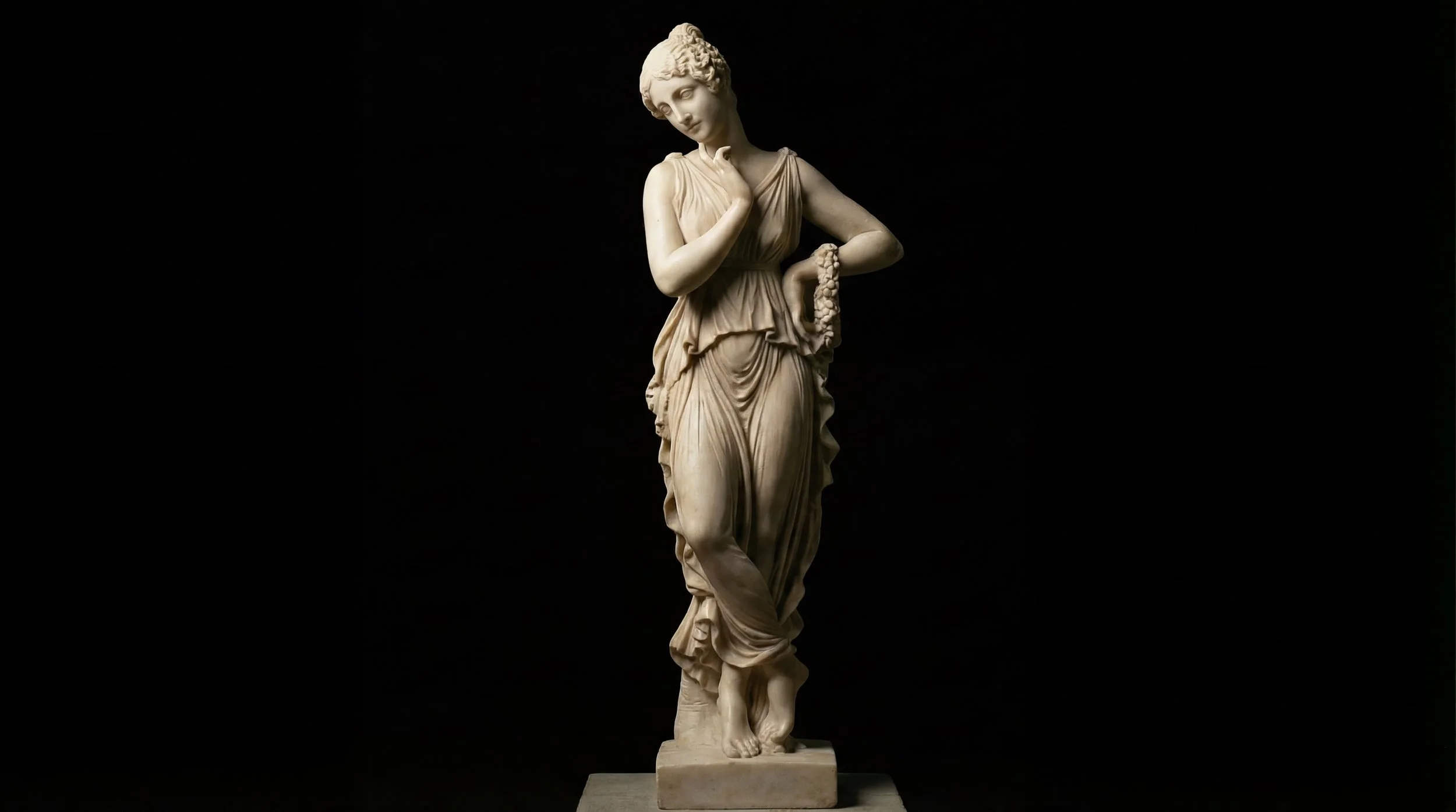 Statua di una donna in marmo, vestita con un abito drappeggiato, con la testa leggermente inclinata e una mano al mento, posata su una base. Chirurgia Plastica e Medicina estetica di viso, corpo e seno.