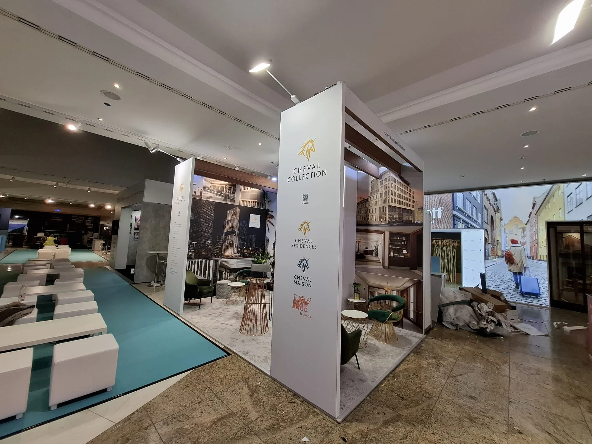 Exhibition booth in Frankfurt, Showroom interior with modern furniture, posters of buildings, and a large digital screen, LED Videowall showing a street scene.