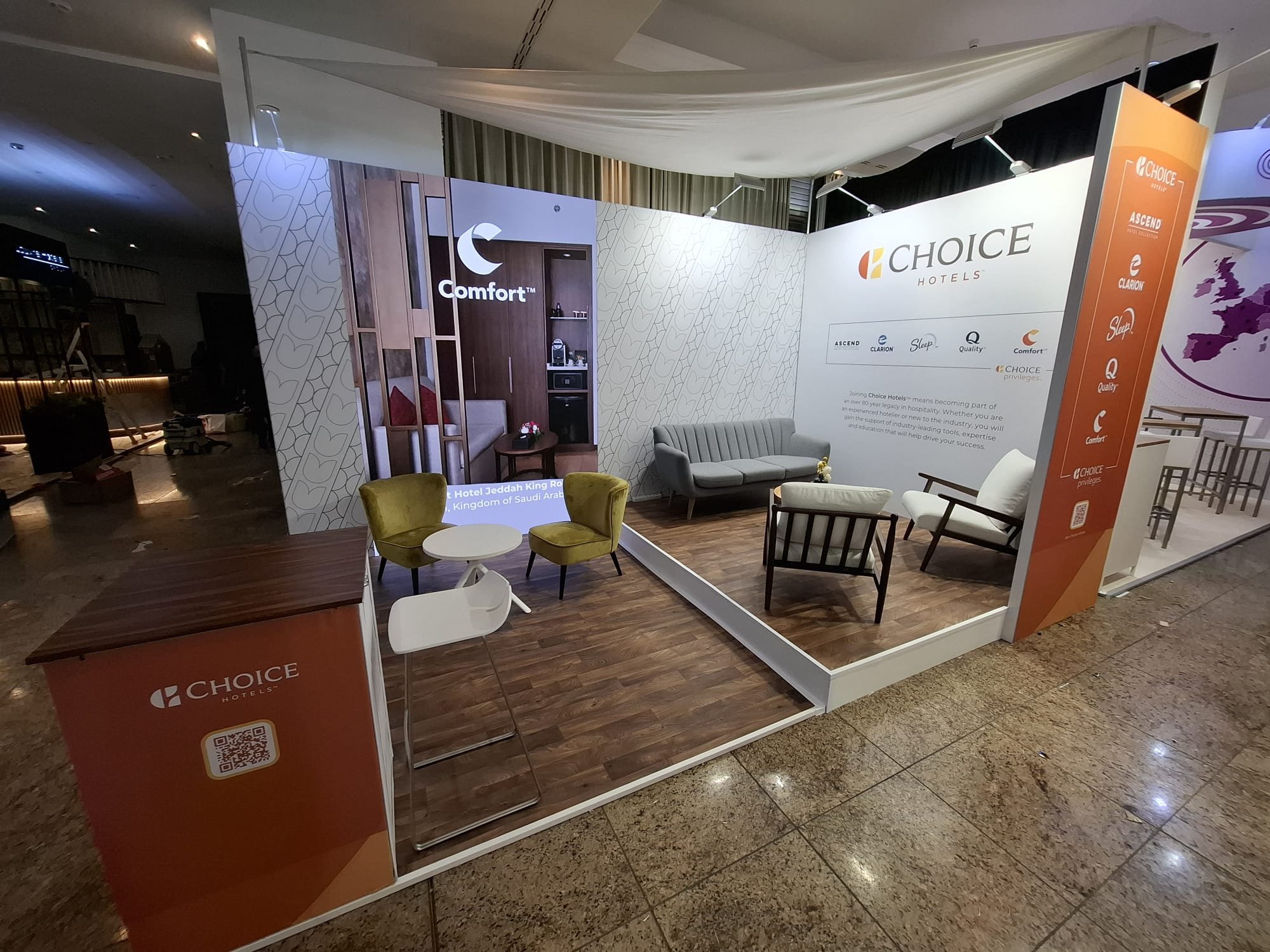 Booth display  featuring a seating area with chairs and sofas, a small table, and promotional banners and a LED Video Wall in Frankfurt