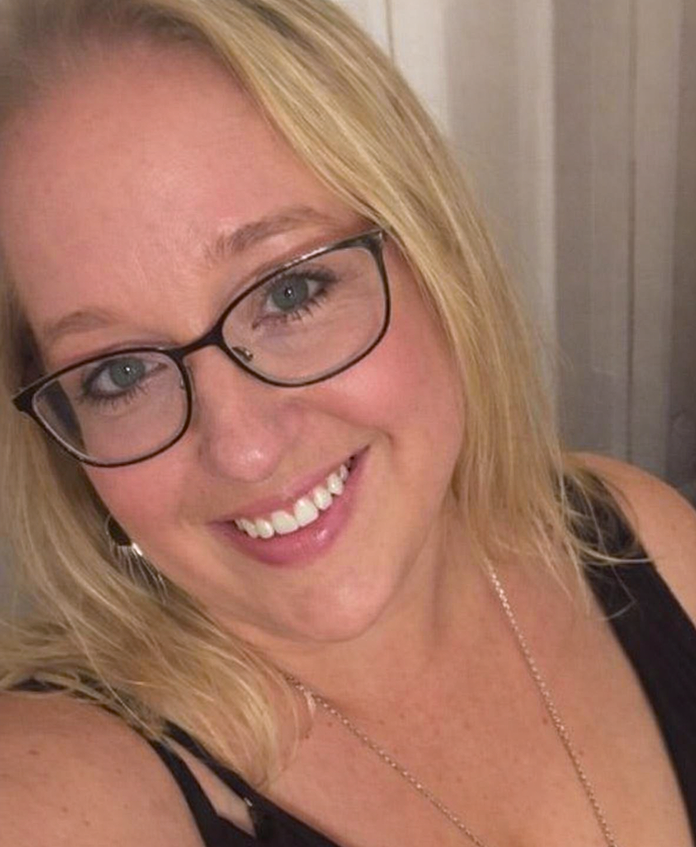 A smiling woman with blonde hair, wearing glasses and a black top.