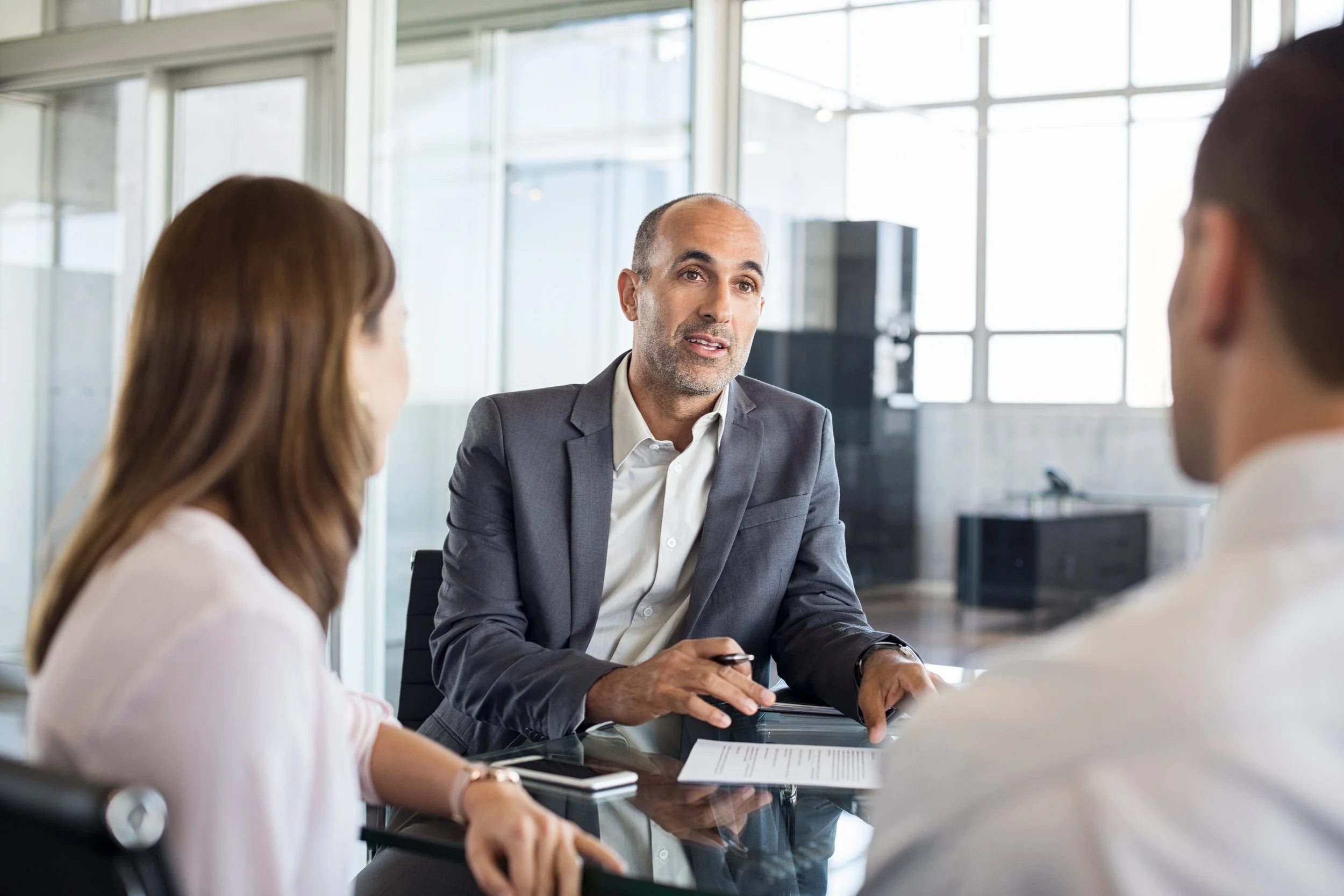Business meeting with three professionals discussing around a table in an office.