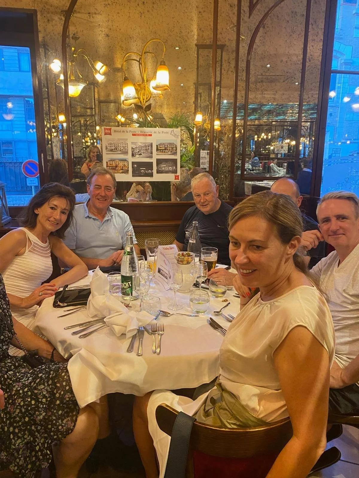 Group of people sitting around a dining table in a restaurant, smiling for the photo.