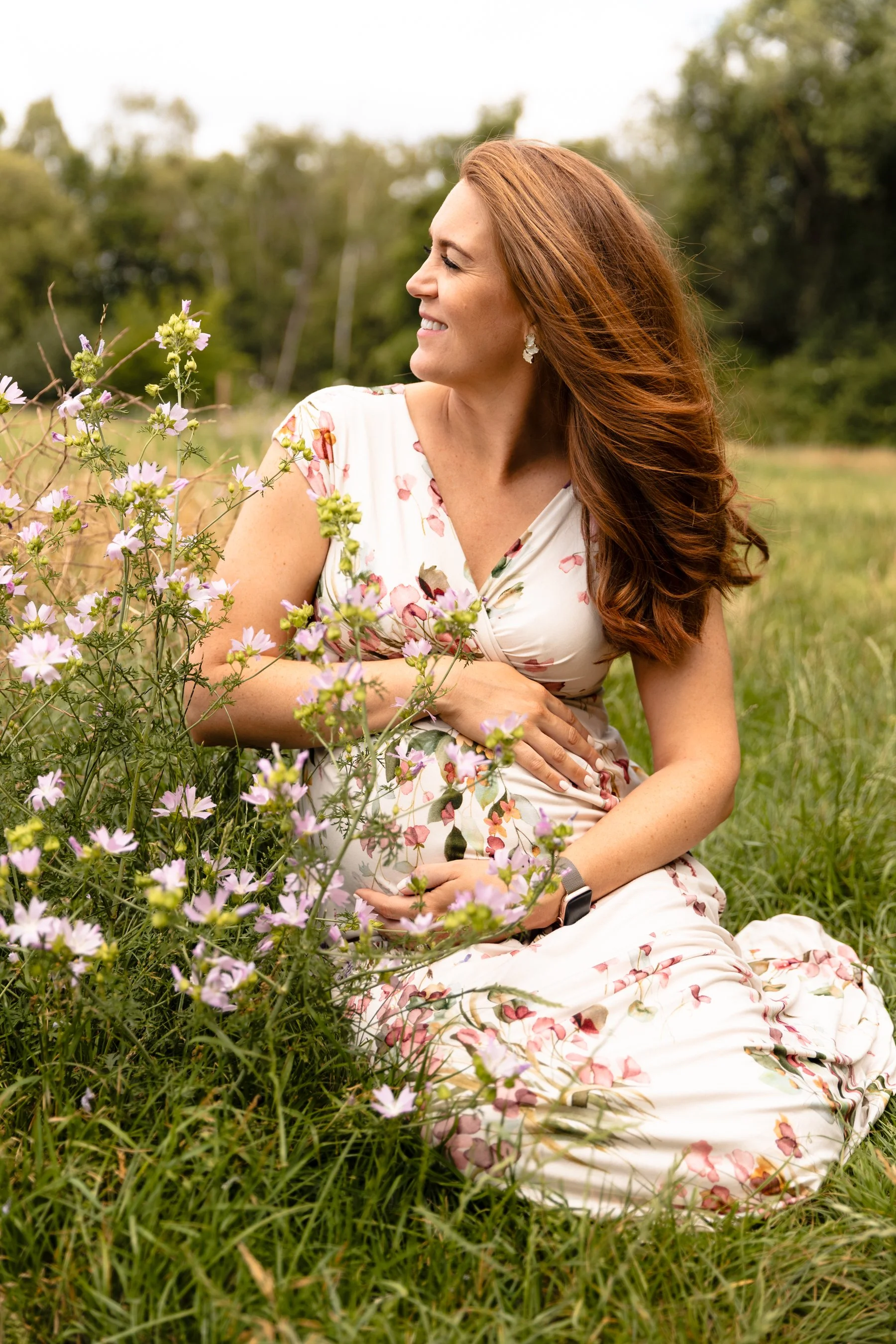 A pregnant mother sitting gracefully amongst colourful wildflowers during an outdoor maternity photoshoot in Earlsfield.