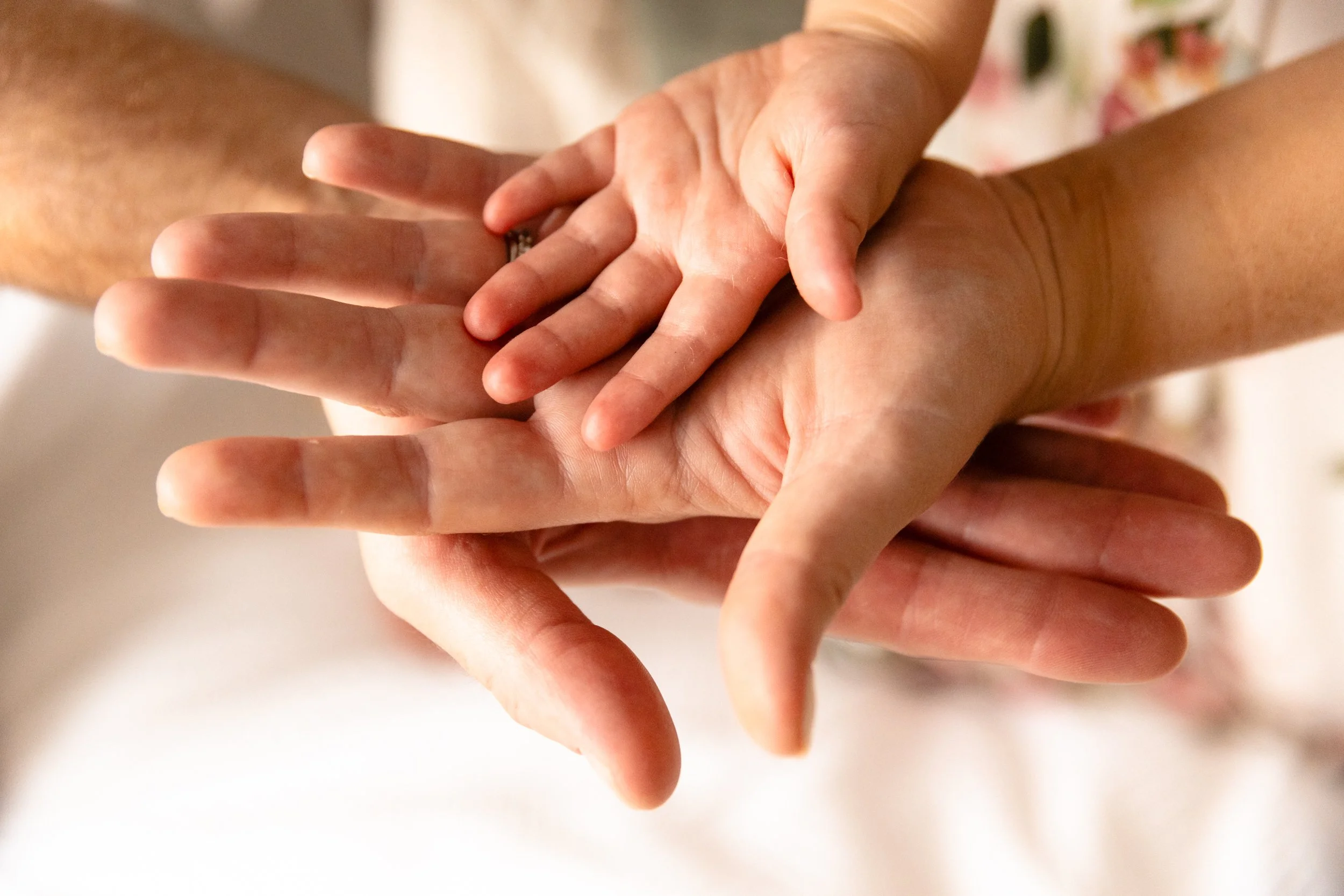 A close-up detail shot of a family of three stacking their hands on top of each other  during a Wandsworth maternity session.