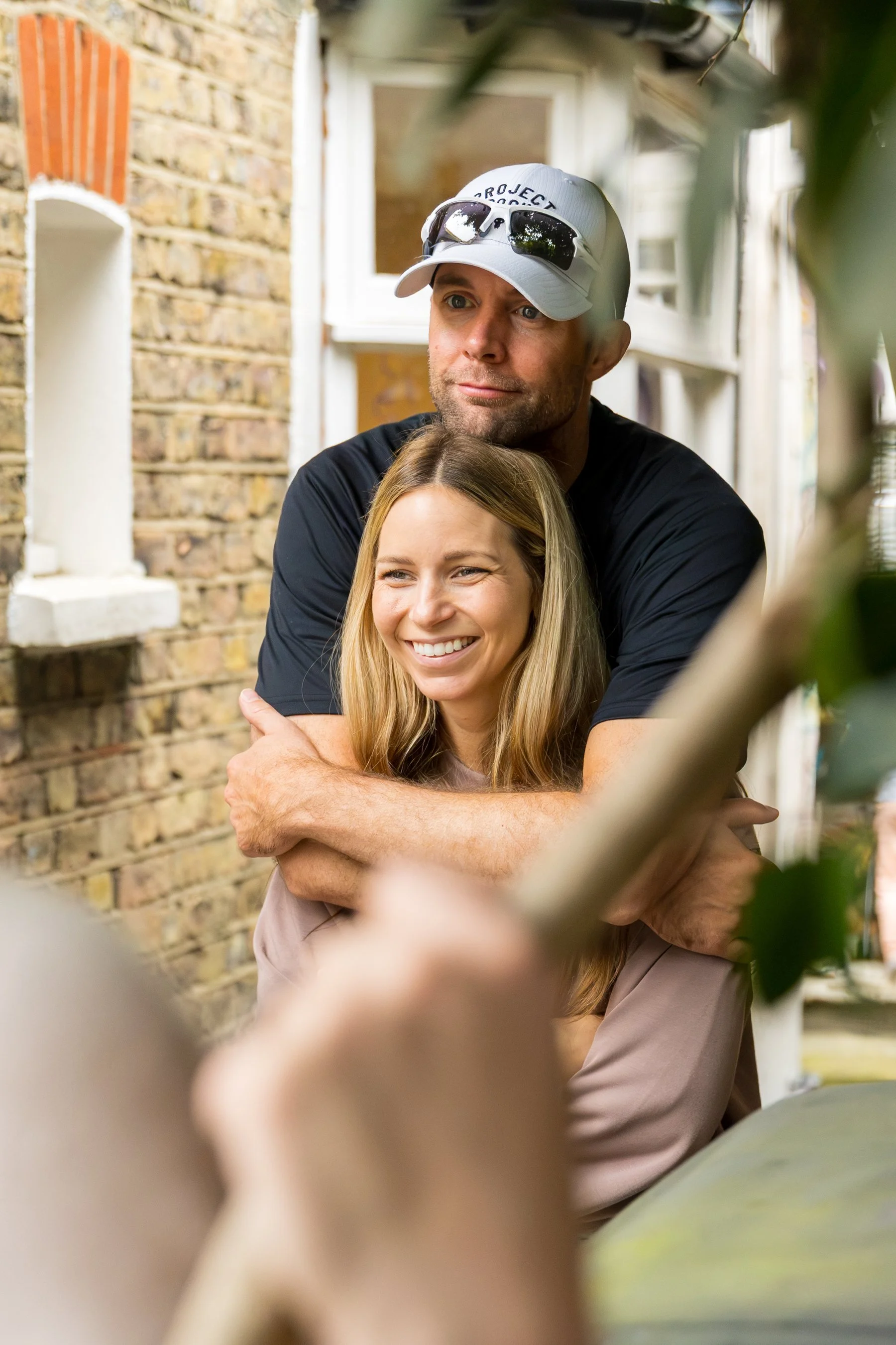 a happy married couple embracing and smiling as they watch their children play at a party in Wandsworth