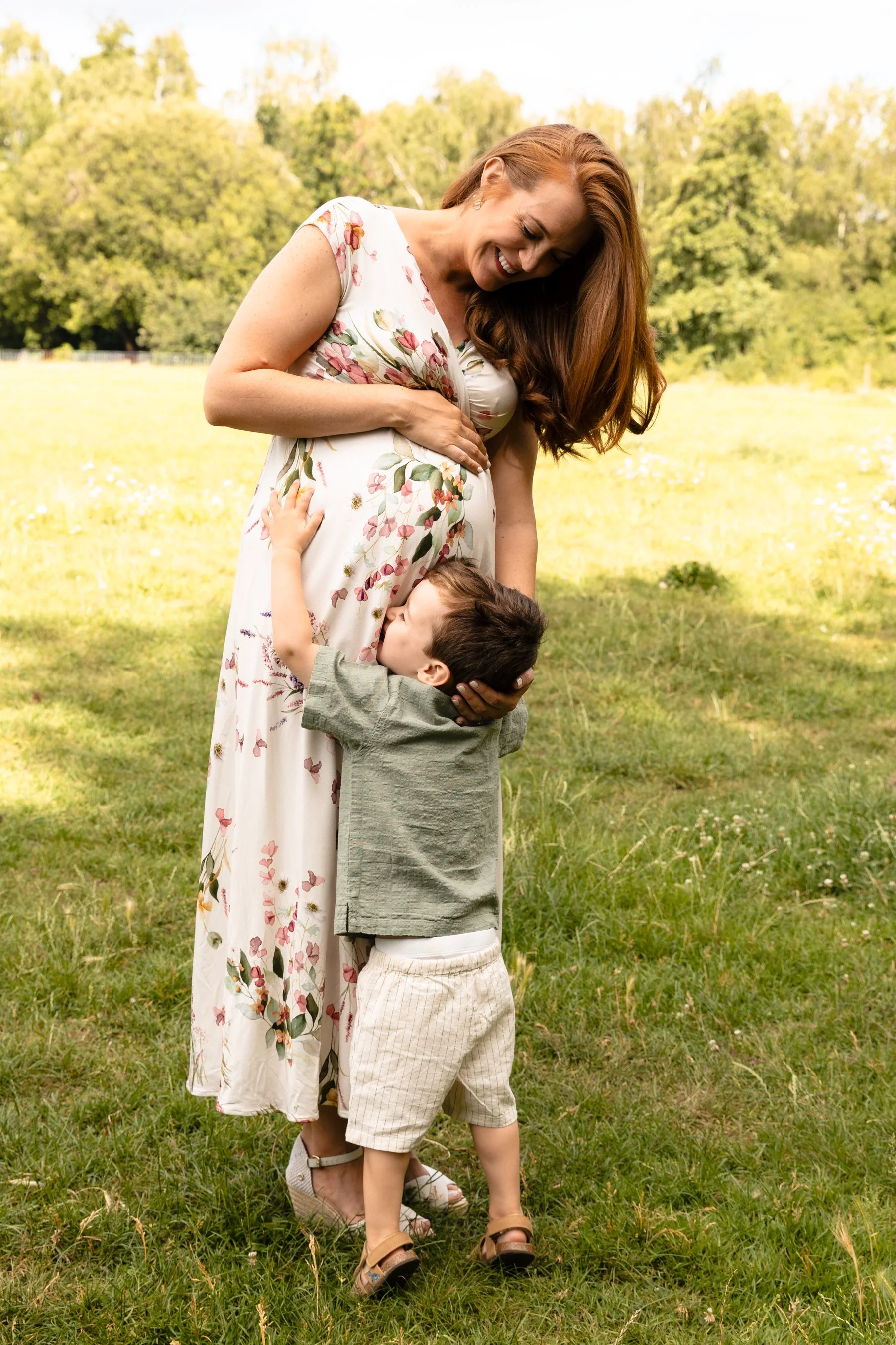 A toddler reaches up to kiss his mother's bump whilst on a family maternity shoot in Earlsfield