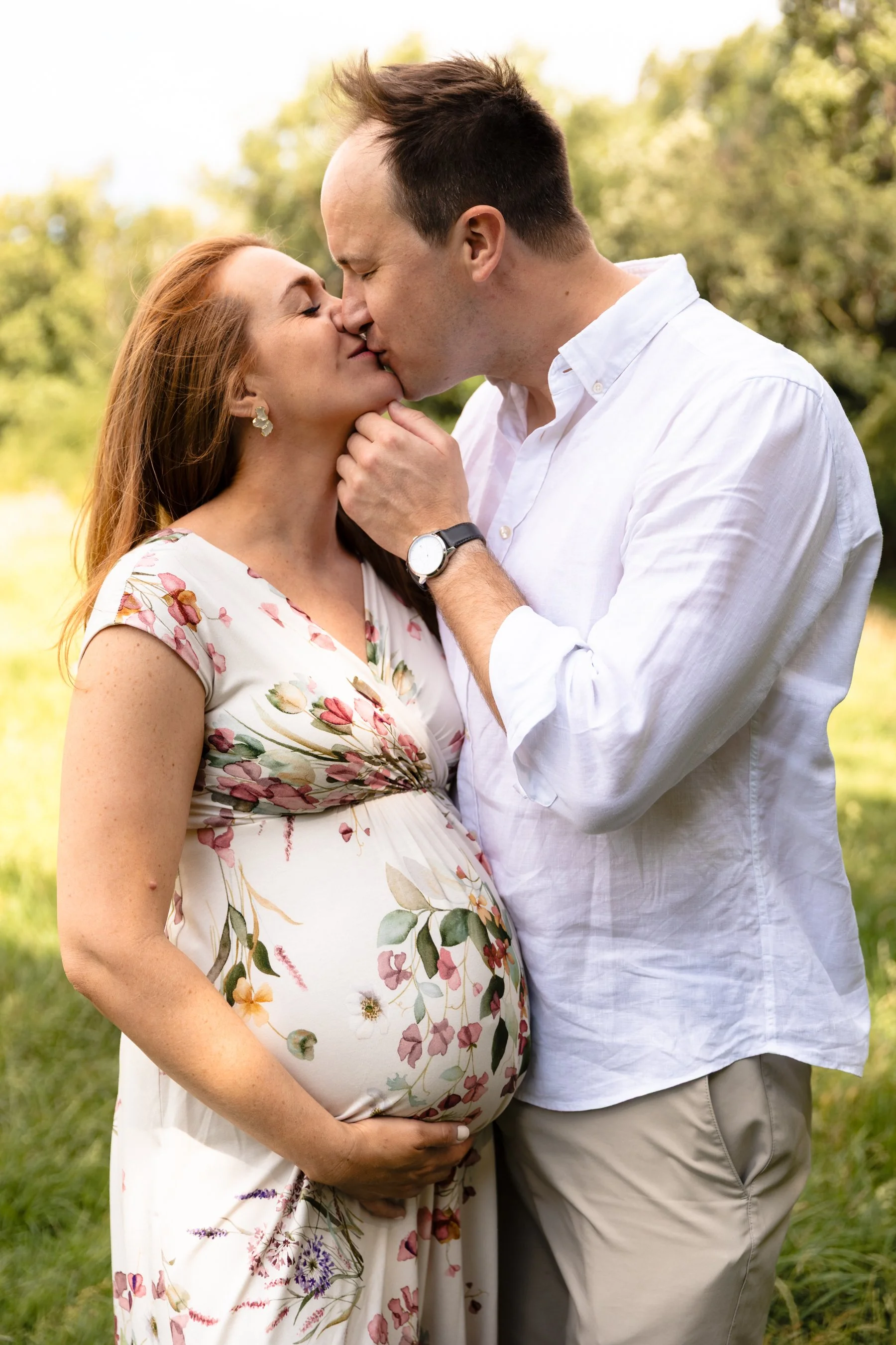 An expectant husband kissing his pregnant wife during an outdoor maternity photoshoot in Wandsworth