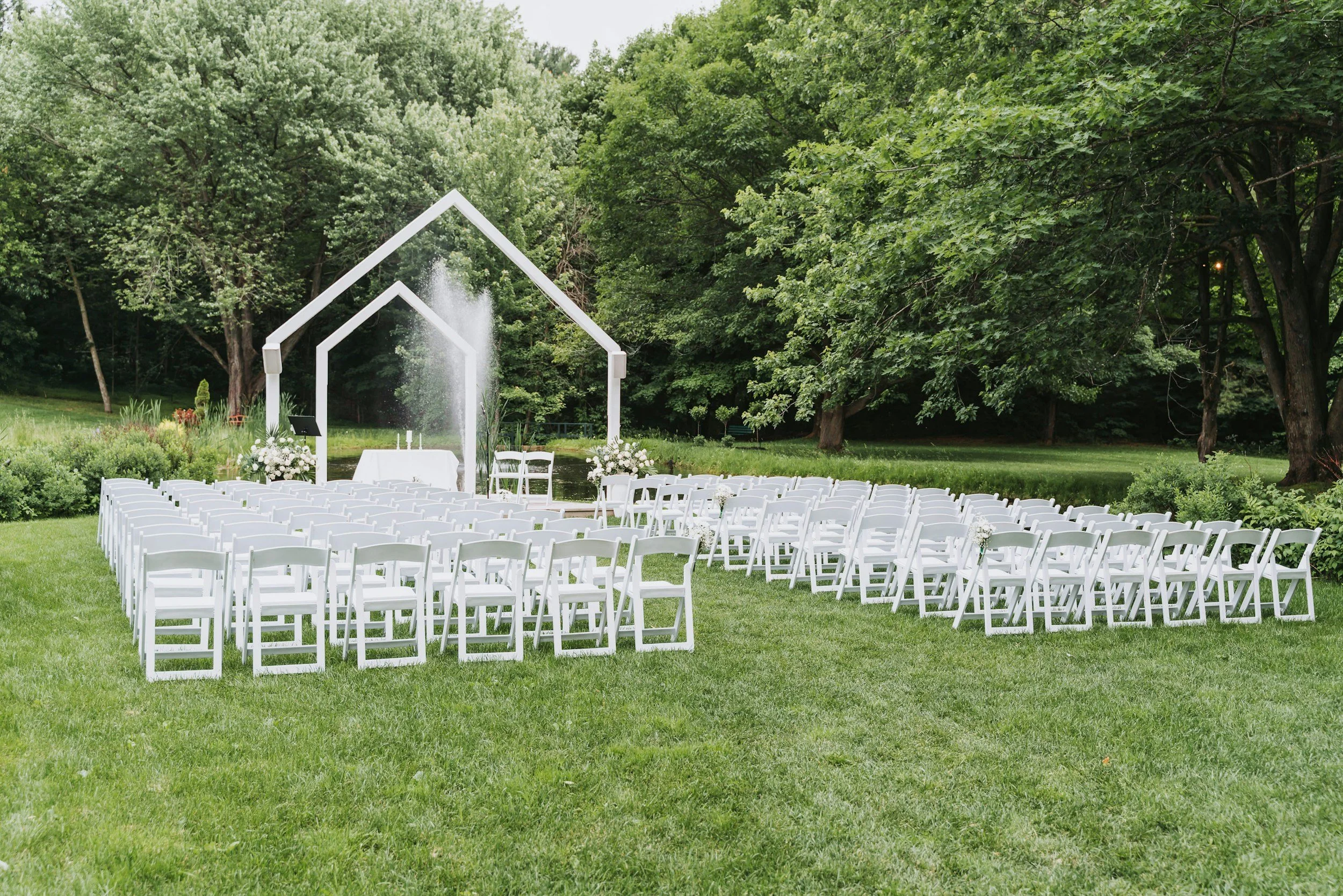 Destination wedding setup with white chairs in a garden.