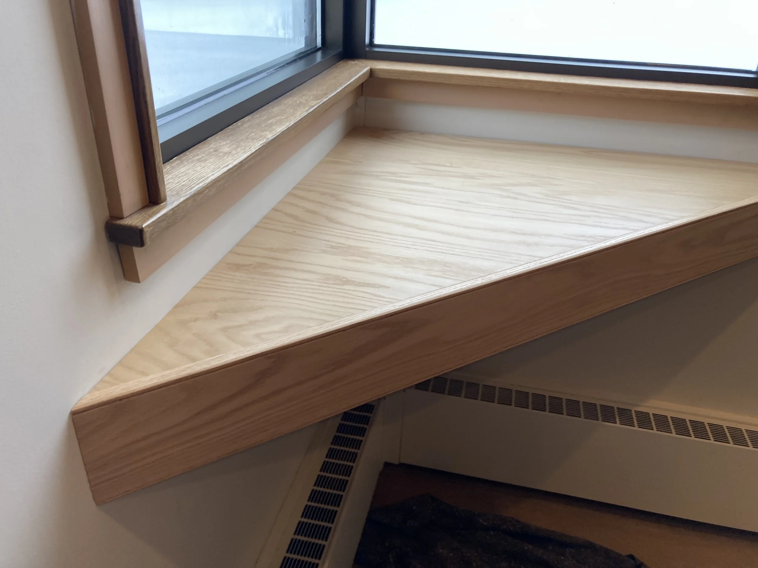 Wooden window sill next to a window with black framing.