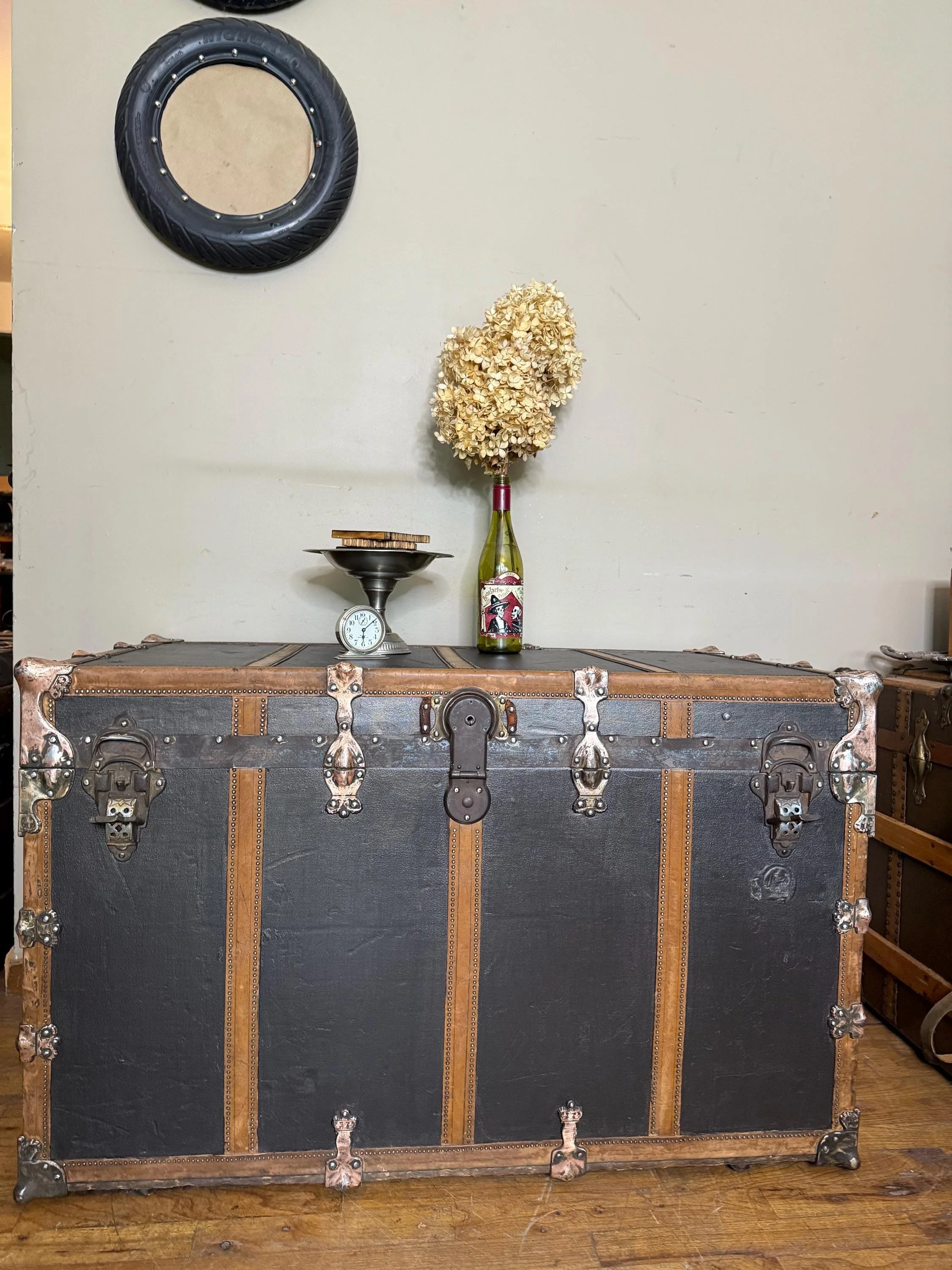 Huge 41-inch wide flat top antique steamer trunk used as an oversized industrial coffee table.