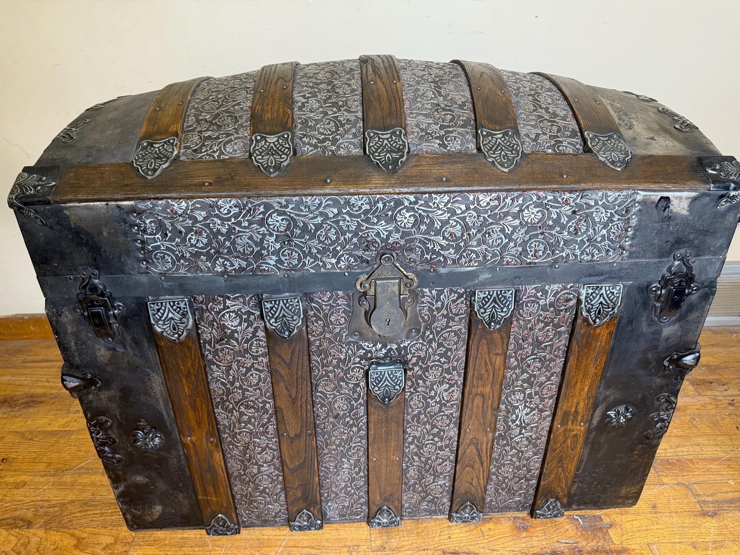 Masterfully restored large high dome steamer trunk with floral embossed tin and walnut slats.