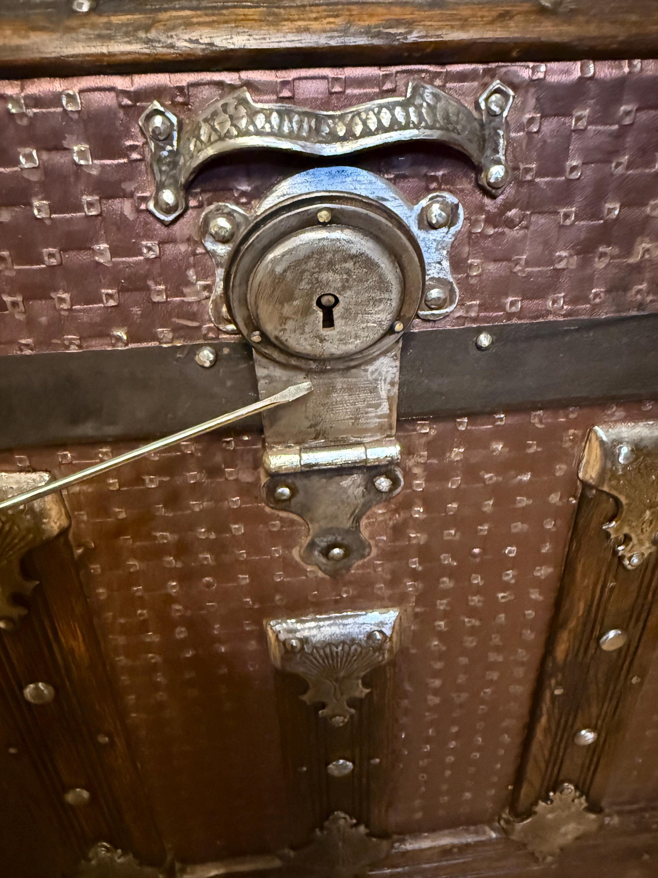 Hand-polished original metal latches and rivets on a high-end heritage steamer trunk.
