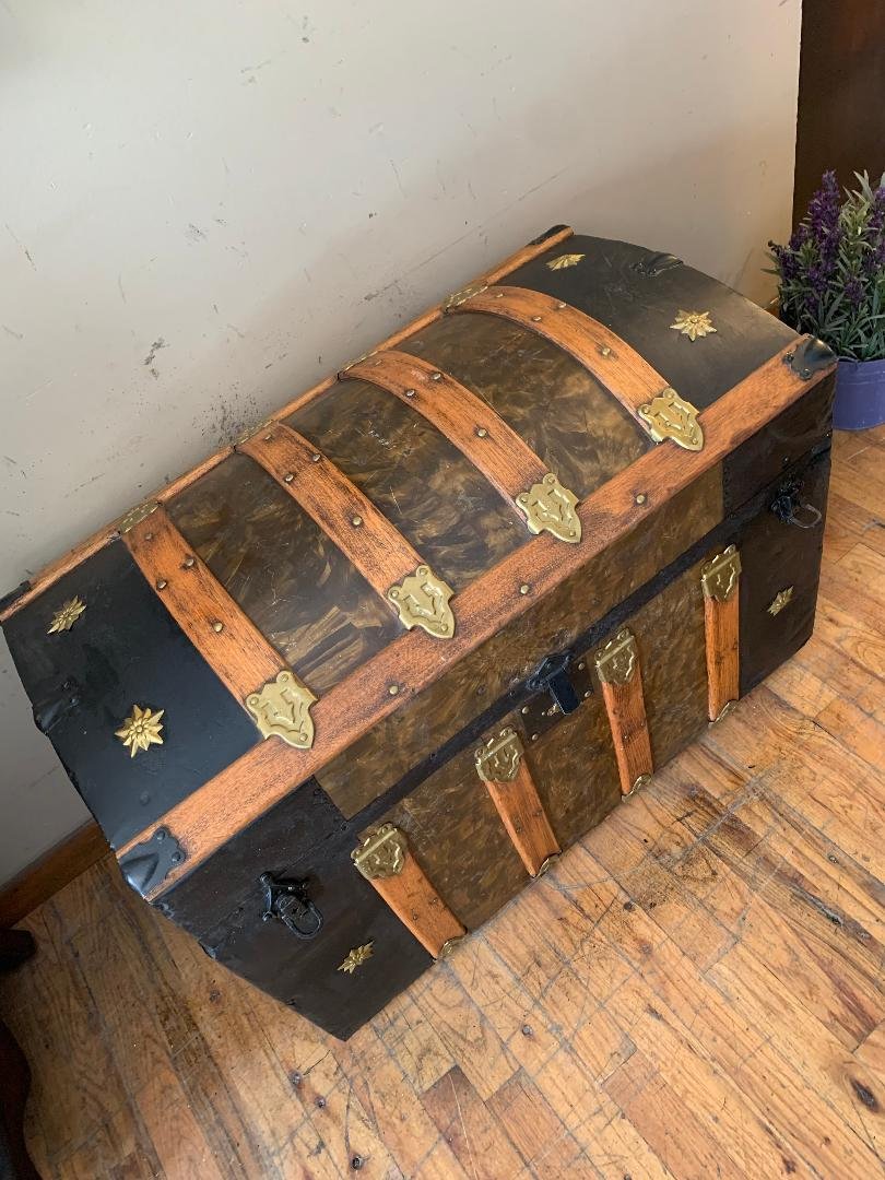 Large 1800s antique dome top steamer trunk featuring original black and brown tin finish.