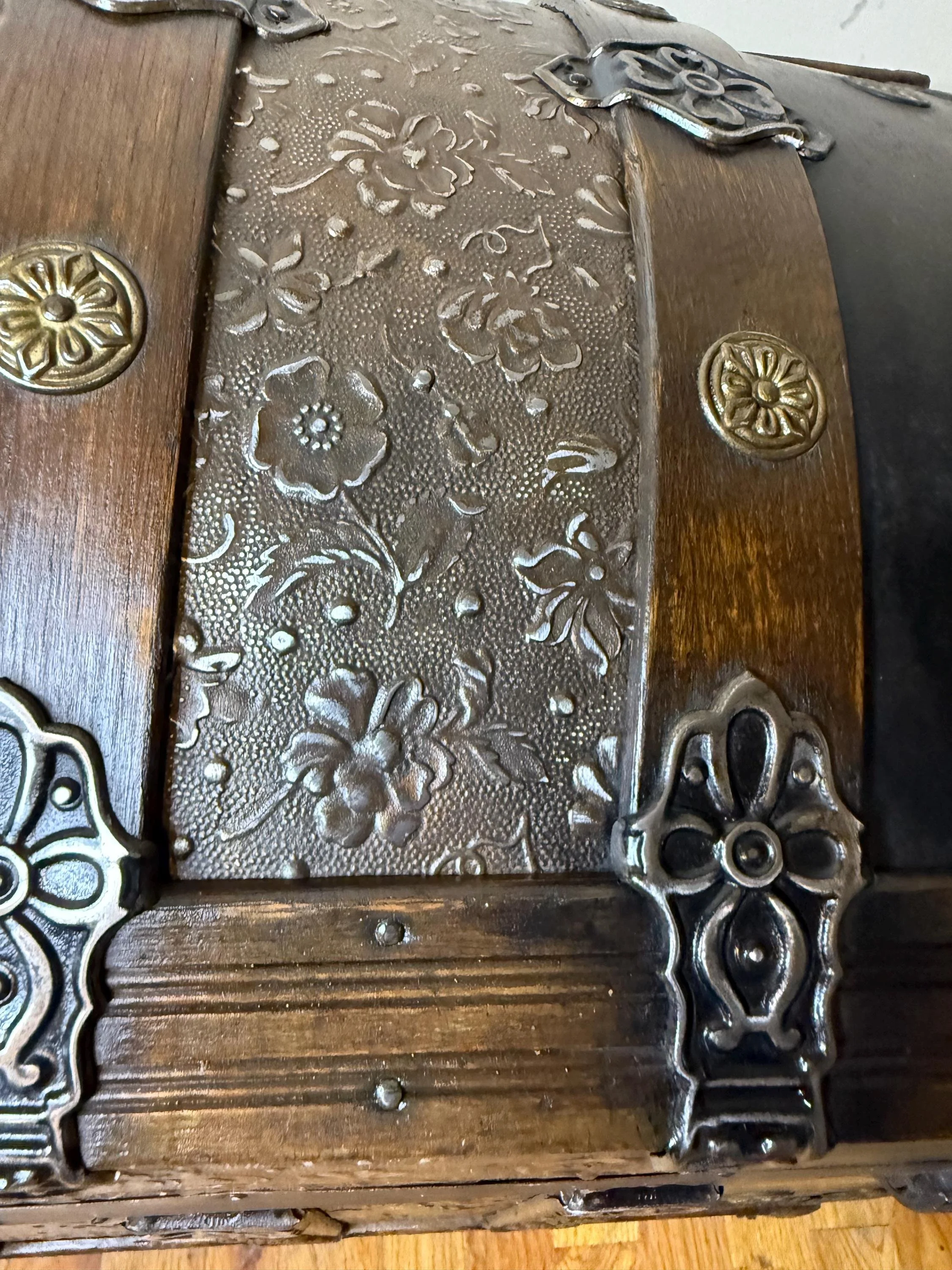 Close-up of floral tin and brass hardware on antique trunk