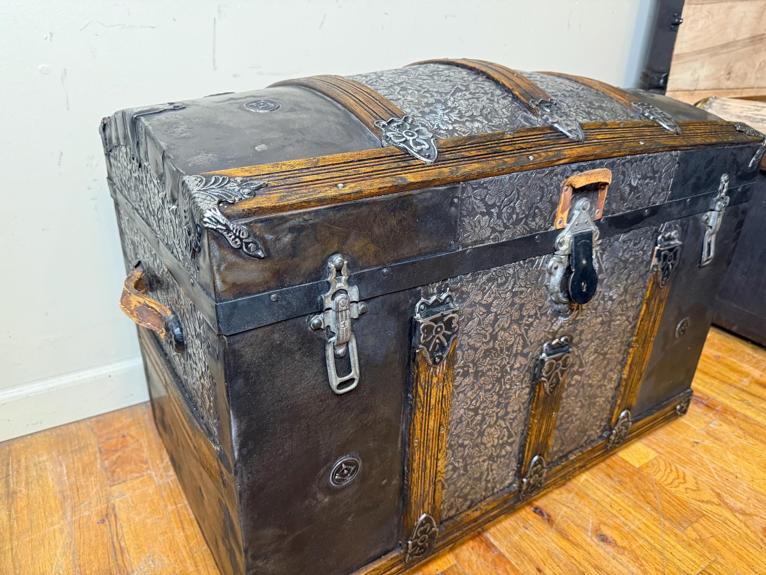 Masterfully restored antique dome top trunk with high-contrast floral embossed tin.