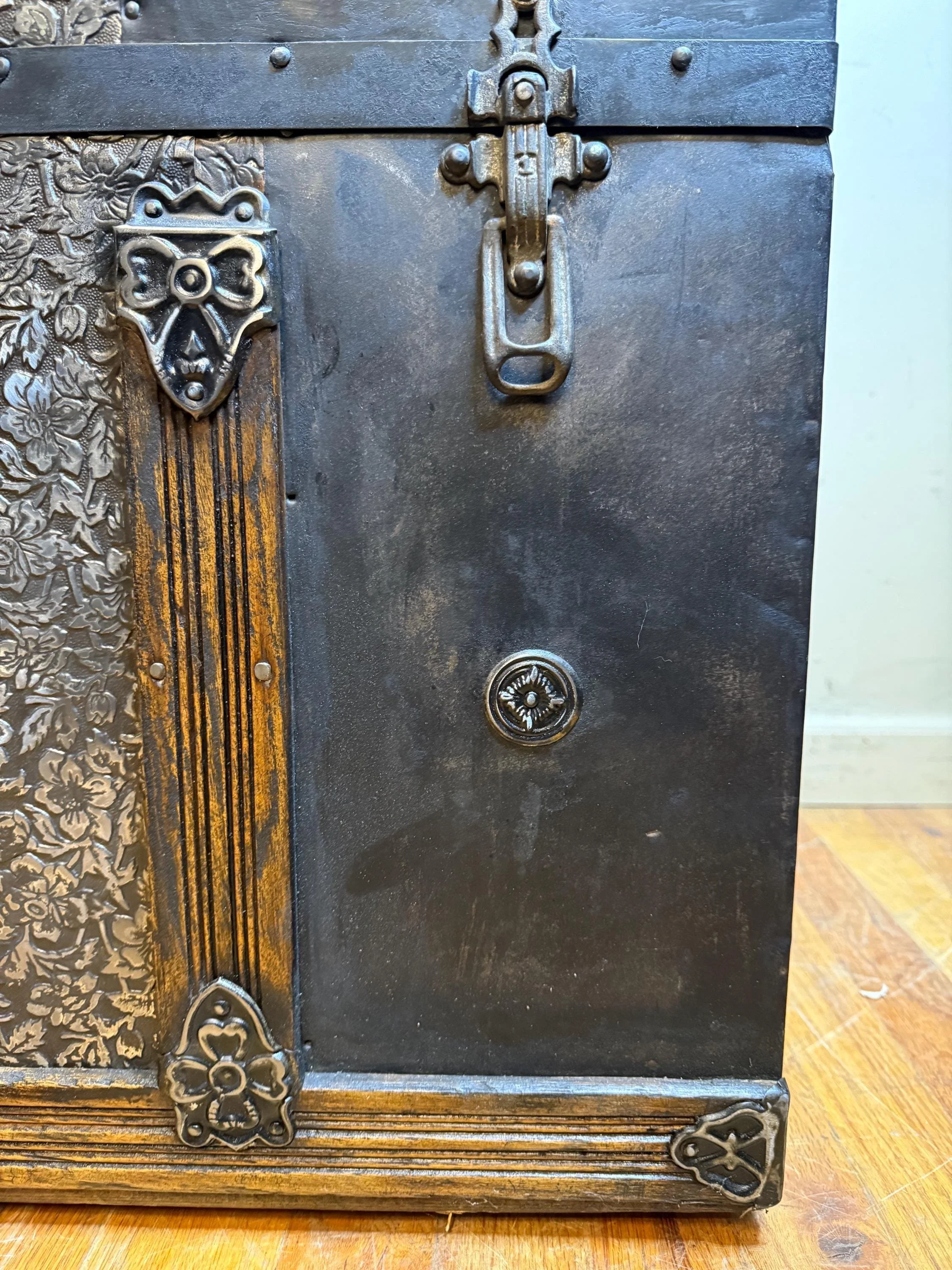 Hand-polished bright metal hardware and rivets on a refinished antique travel chest.