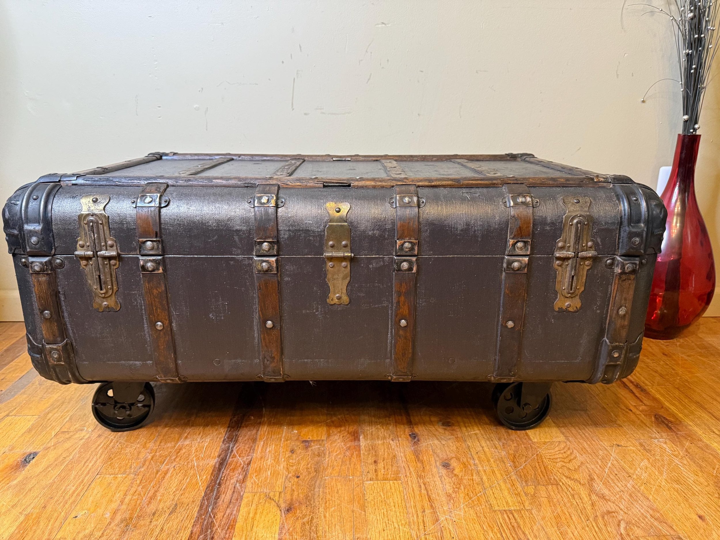 Close-up of 4-inch heavy-duty steel wheels on a refinished antique storage trunk.