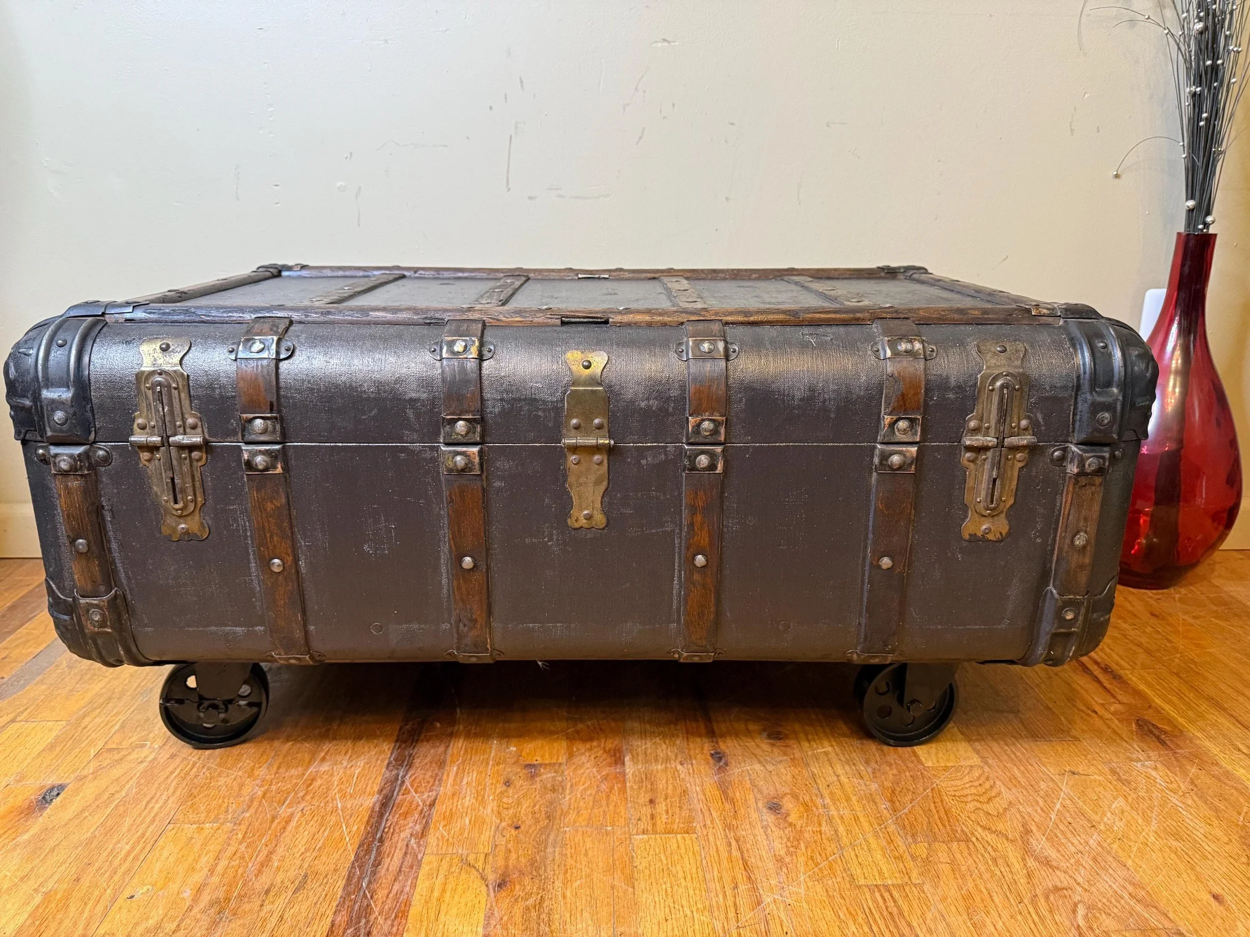 Close-up of 4-inch heavy-duty steel wheels on a refinished antique storage trunk.