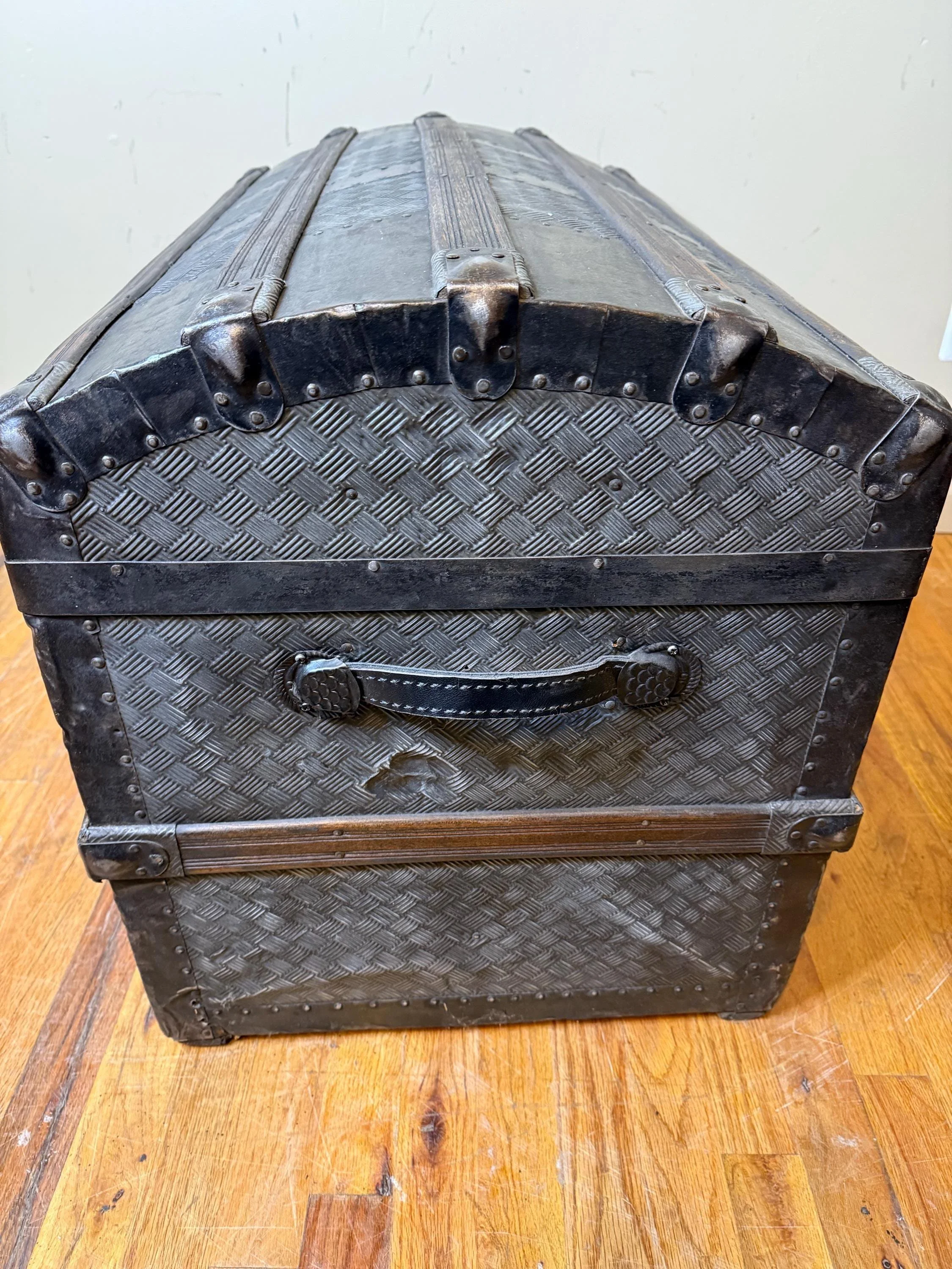 Victorian steamer chest with crosshatch embossed tin exterior and leather handles
