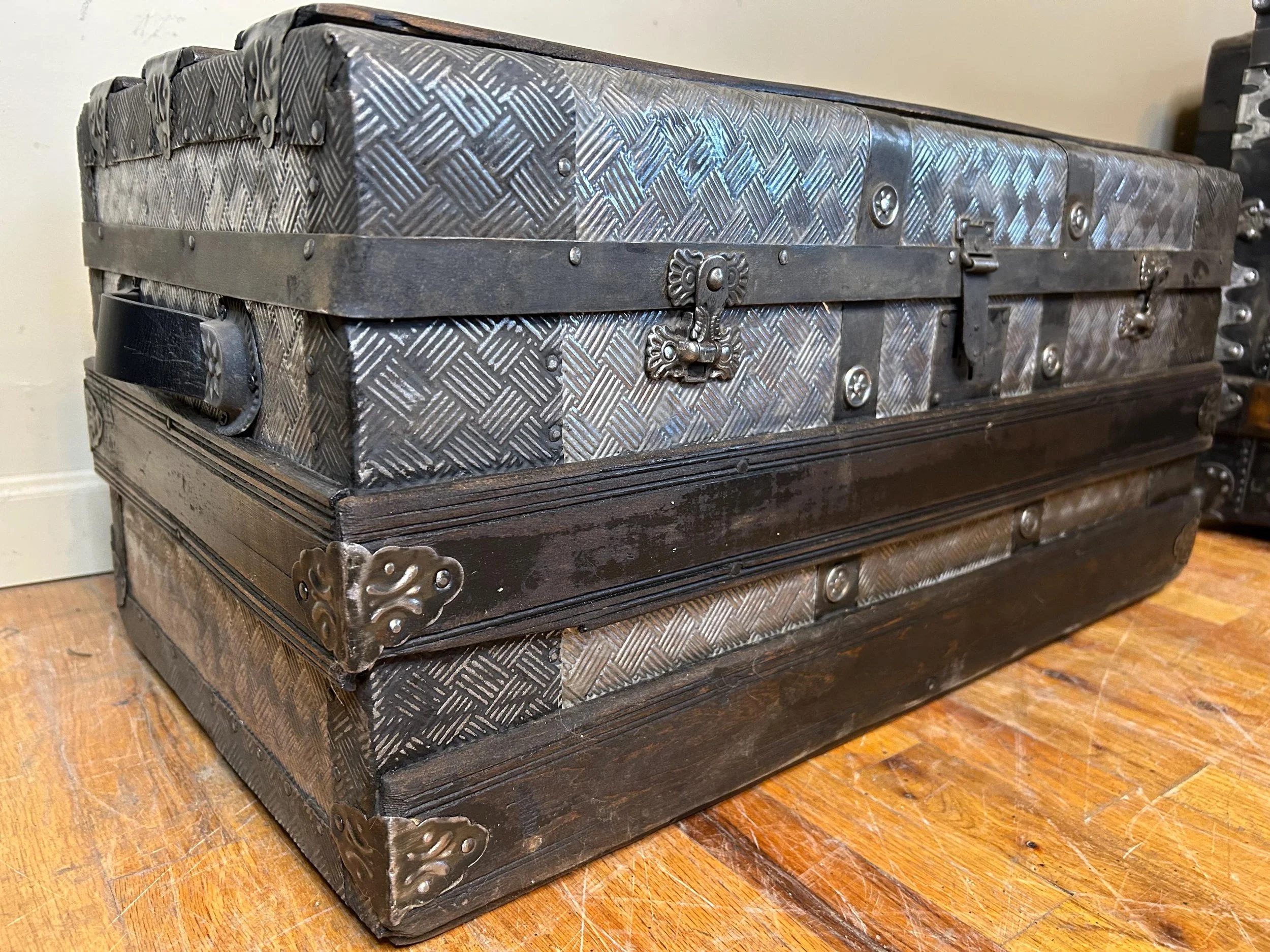 Small antique steamer trunk with embossed tin exterior and walnut wood slats