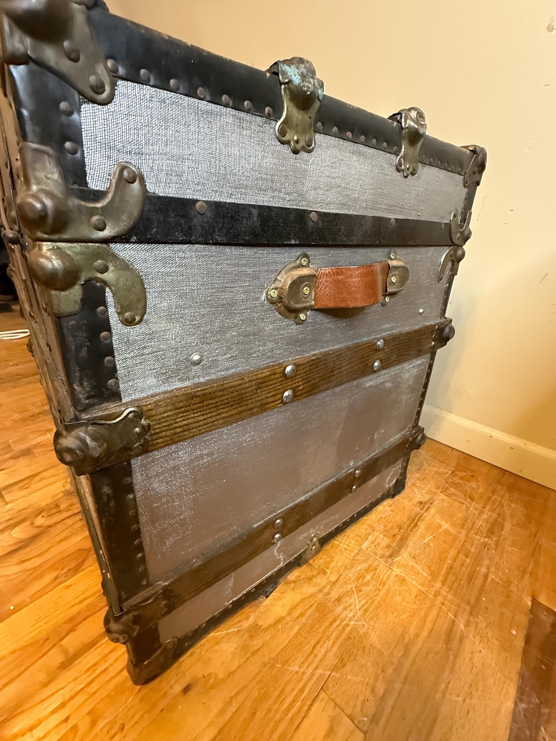 Heavy-duty antique metal corner protectors on a flat top canvas trunk professionally restored.