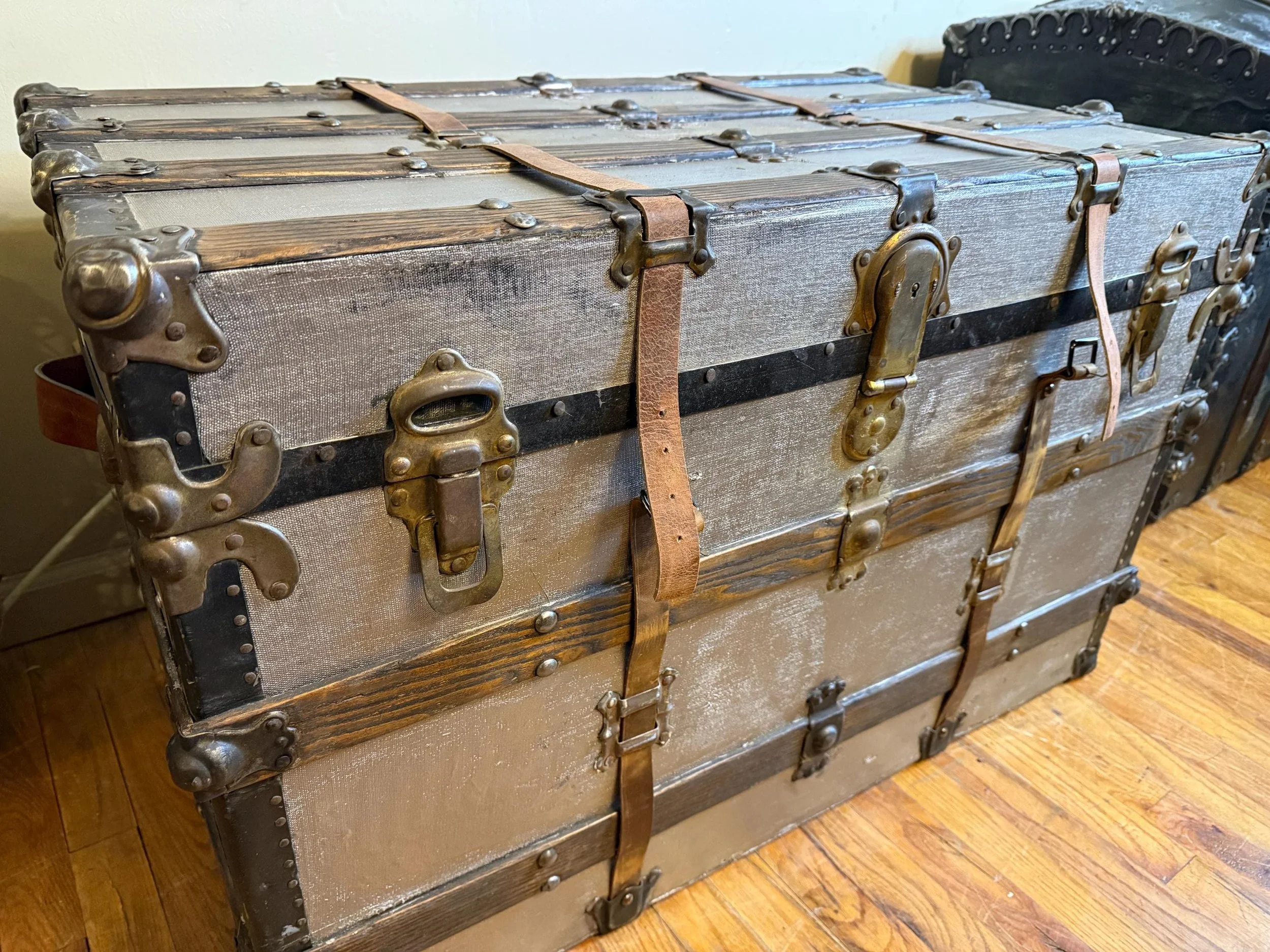 Hand-buffed metal latches and rivets on a silver metallic refinished trunk.