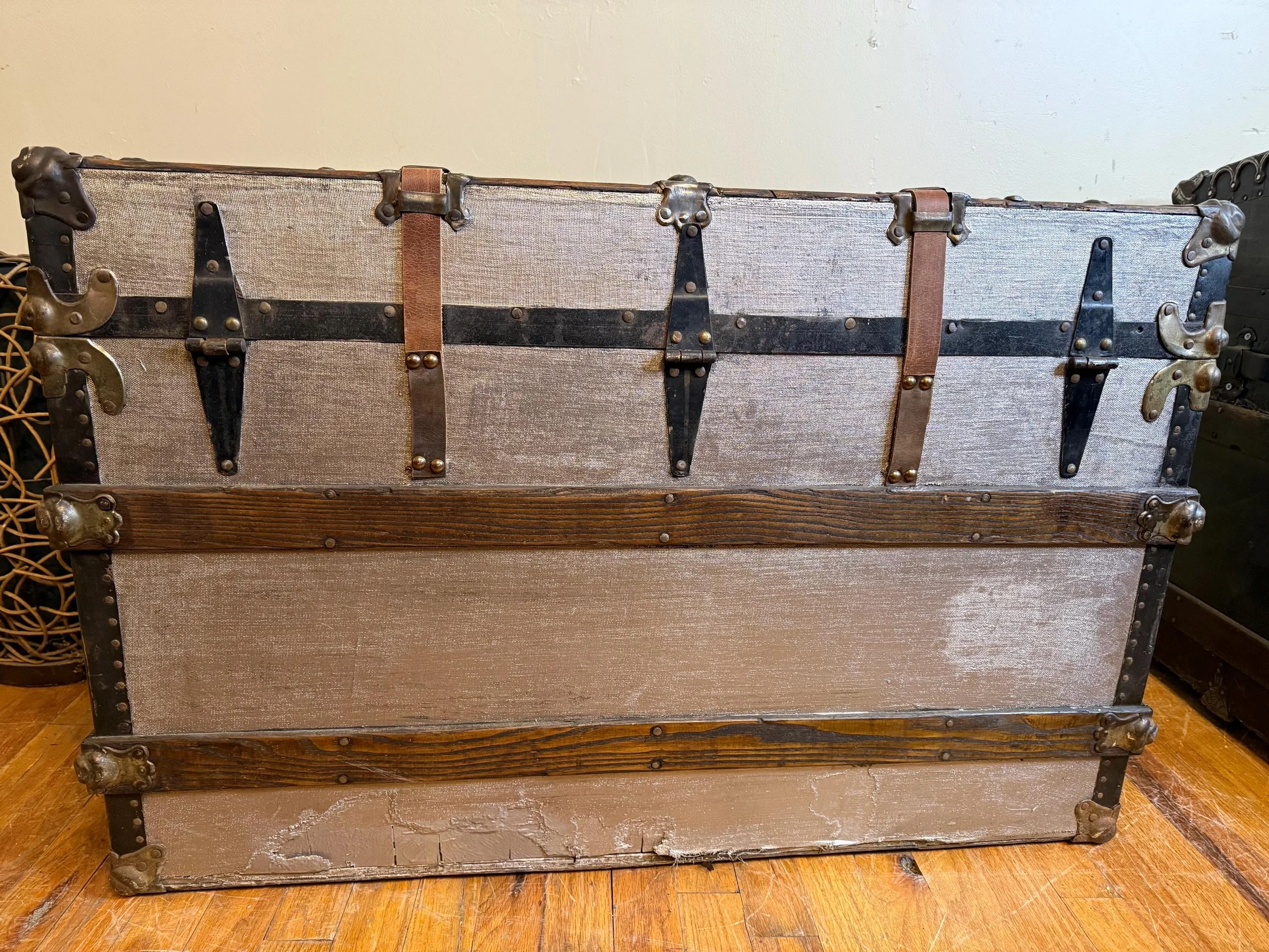 Back view and metal buckles on a silver metallic antique trunk