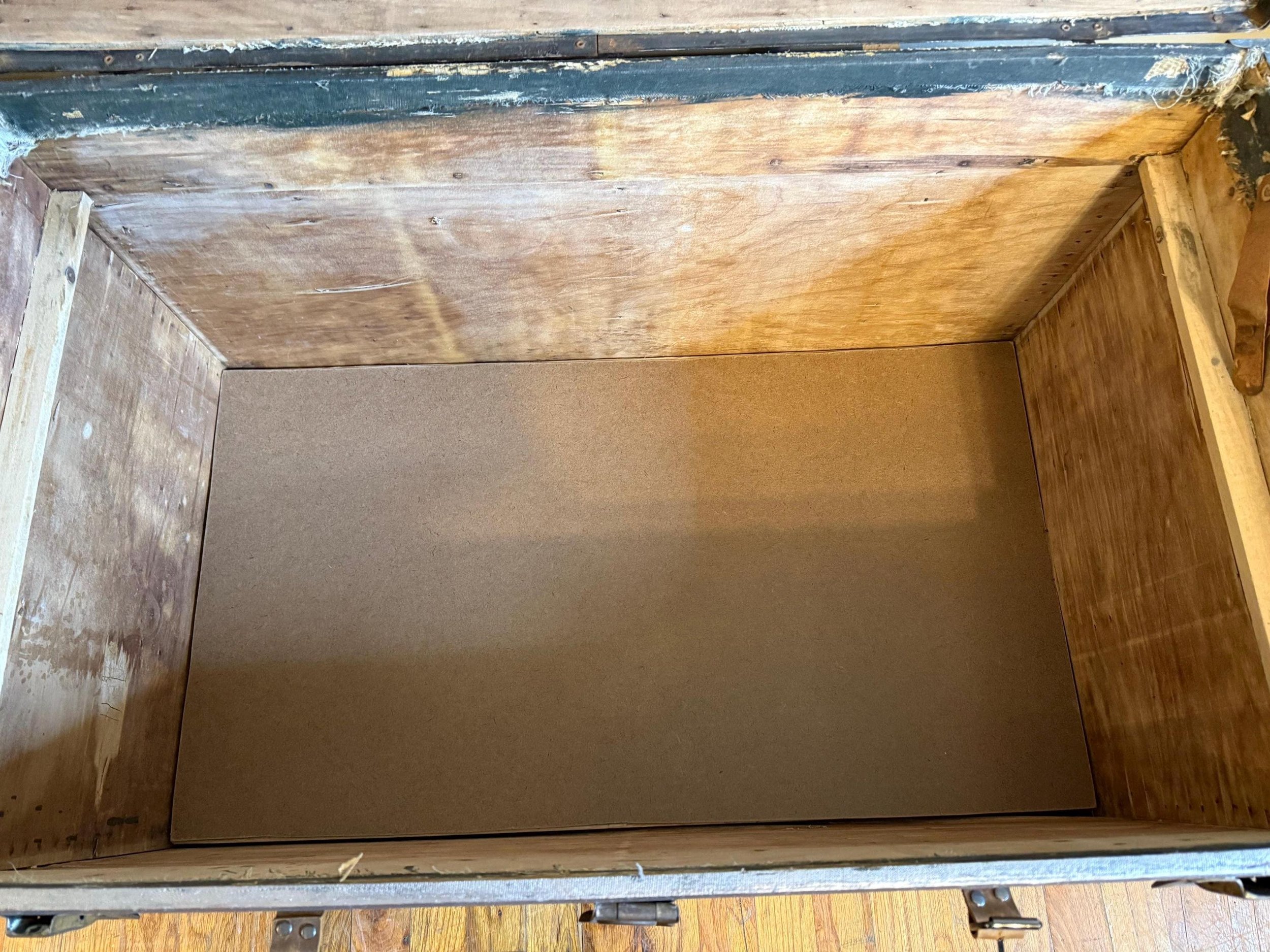 Detail of the secret false bottom hidden storage compartment inside an antique trunk