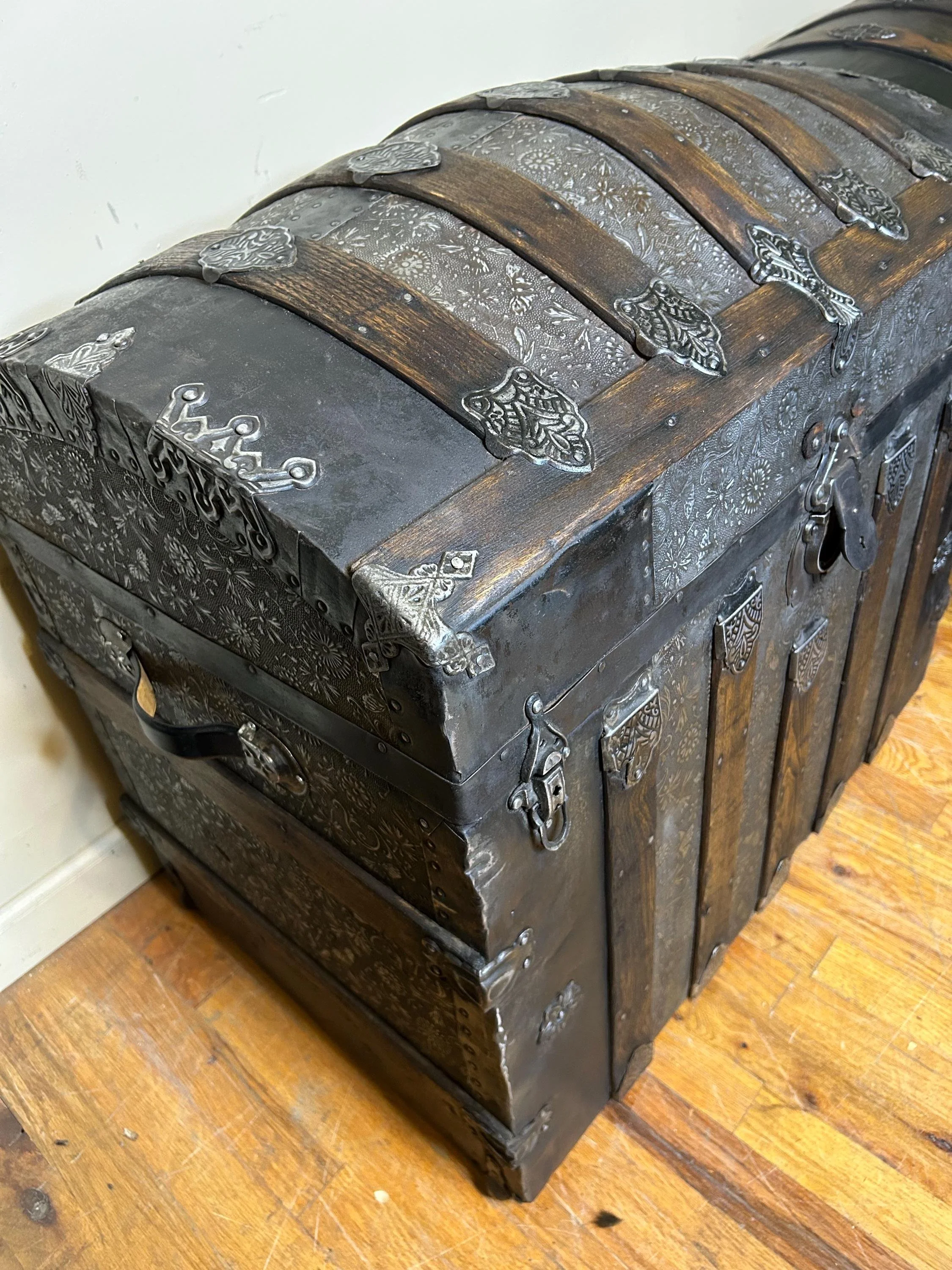 Dramatic angle view of a rare floral embossed Saratoga trunk for heritage interiors.