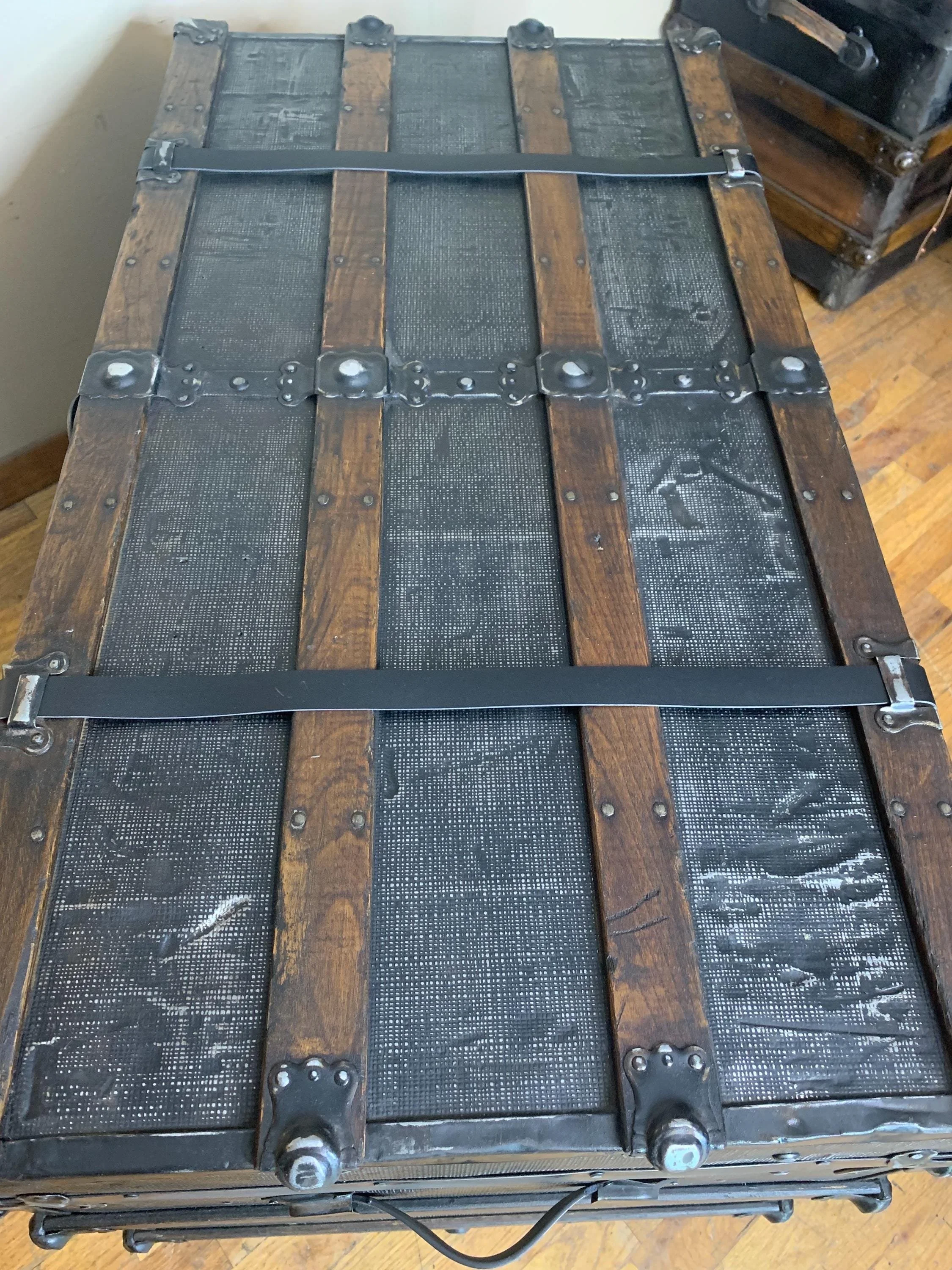 Large flat top antique trunk repurposed as an oversized industrial coffee table.