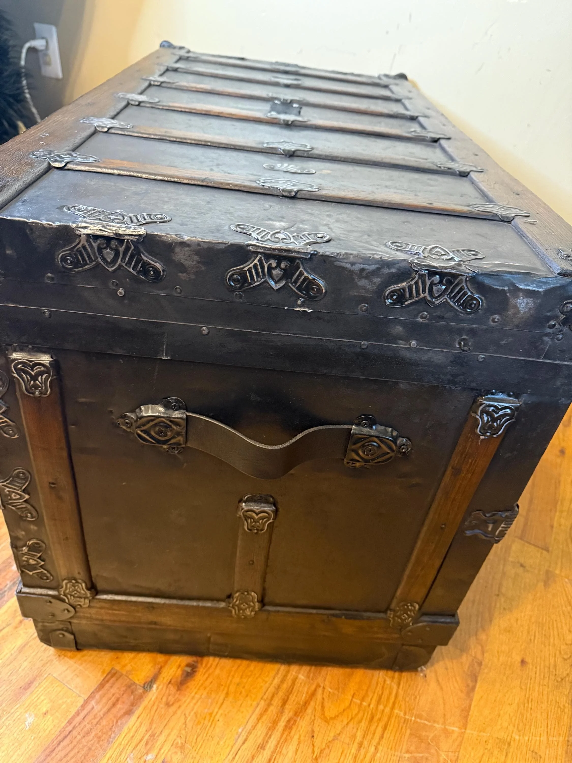 Detailed view of custom leather straps and metal buckles on a refinished trunk.