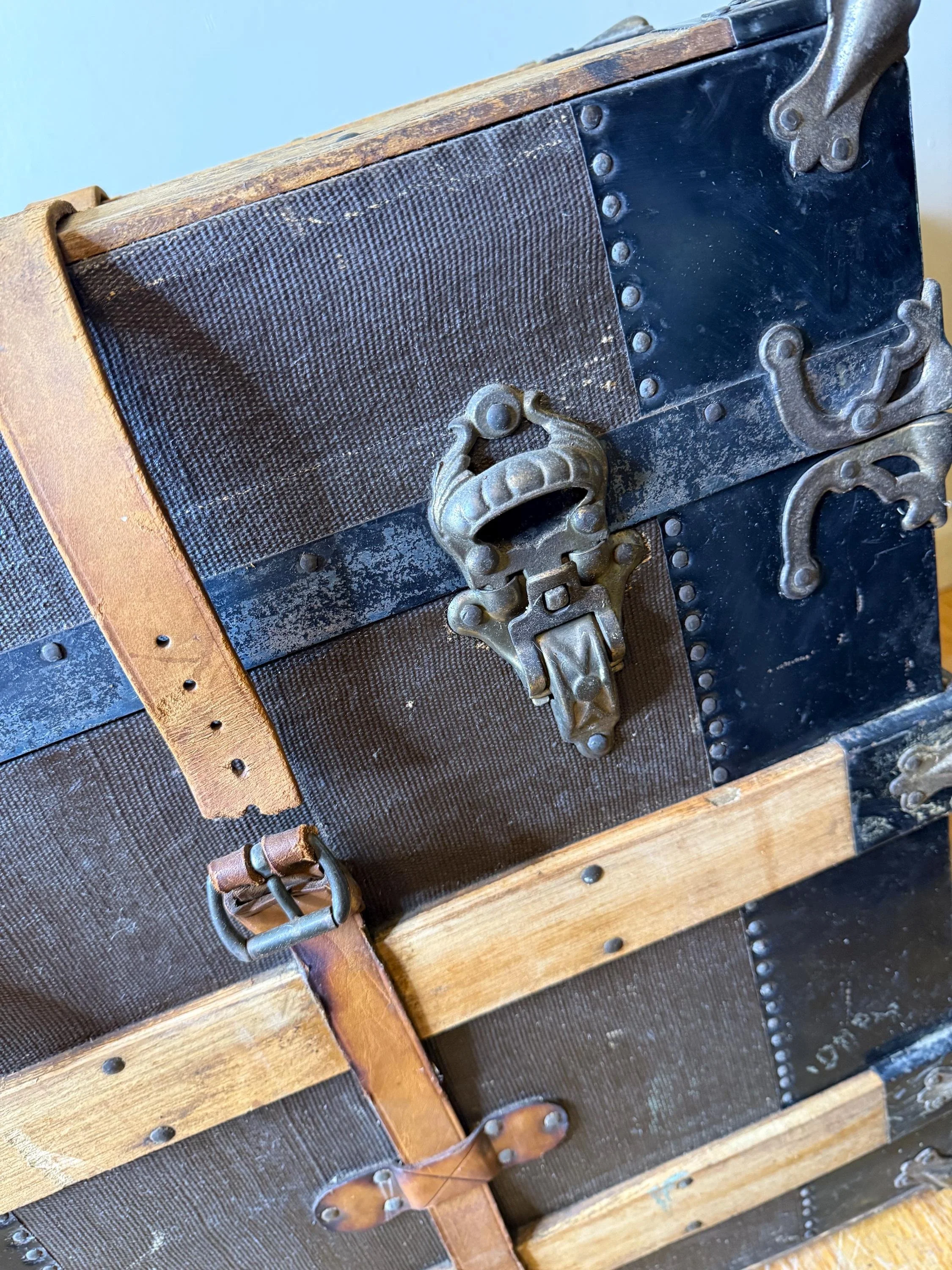 Detailed view of the original leather straps and oversized brass studs on a heritage chest.
